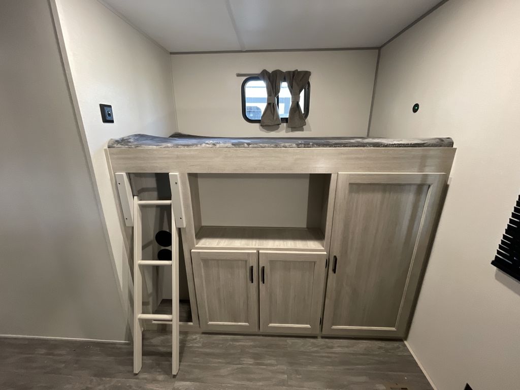 This RV rental features a comfortable bunk bed with a ladder, built-in storage cabinets, and a window, optimizing space for travel.. Forest River Aurora Aurora 2024