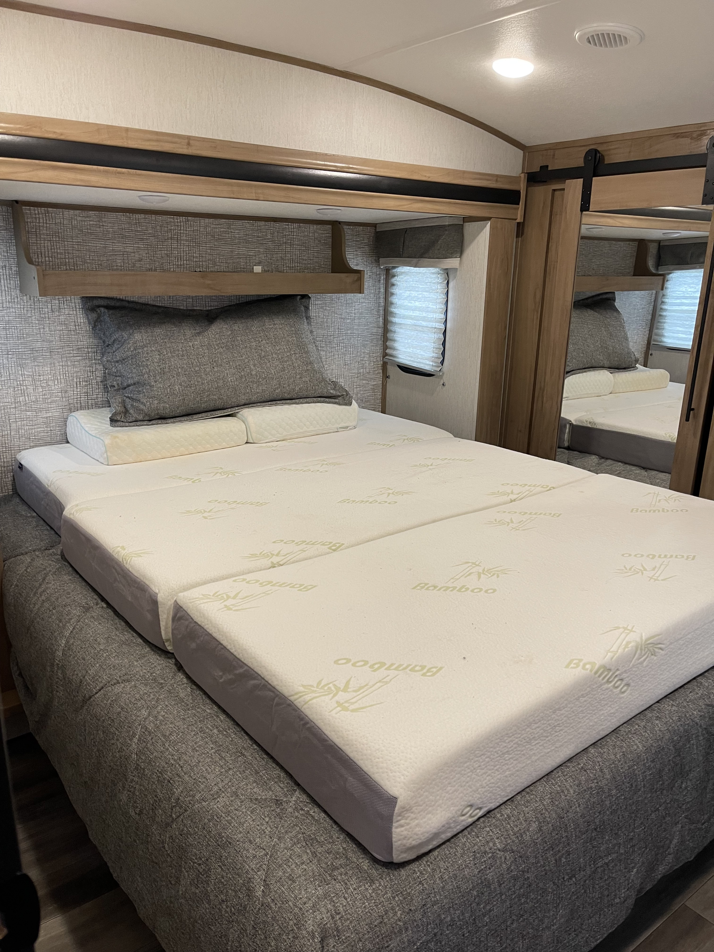 RV rental bedroom featuring a two-piece Bamboo memory foam mattress, sleek headboard, and mirrored wardrobe.. Forest River Sabre 2024