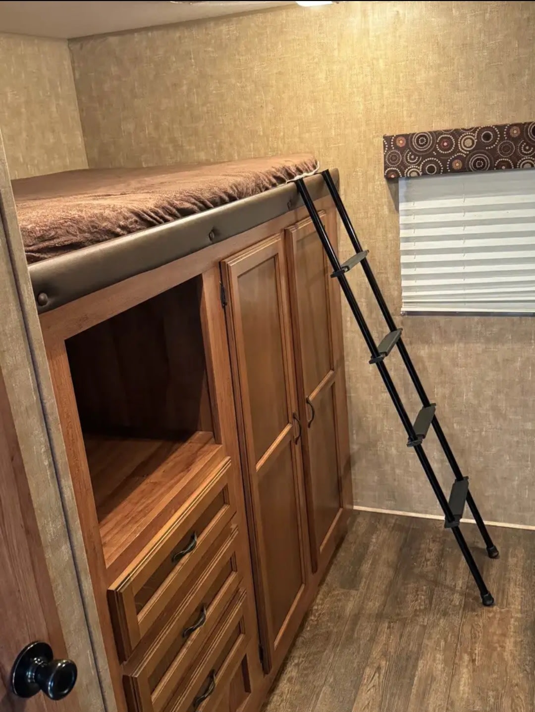 Inside an RV rental: a cozy bunk bed with ladder sits atop built-in wooden cabinets and drawers.. KZ Kz spree Bhs 322 2015
