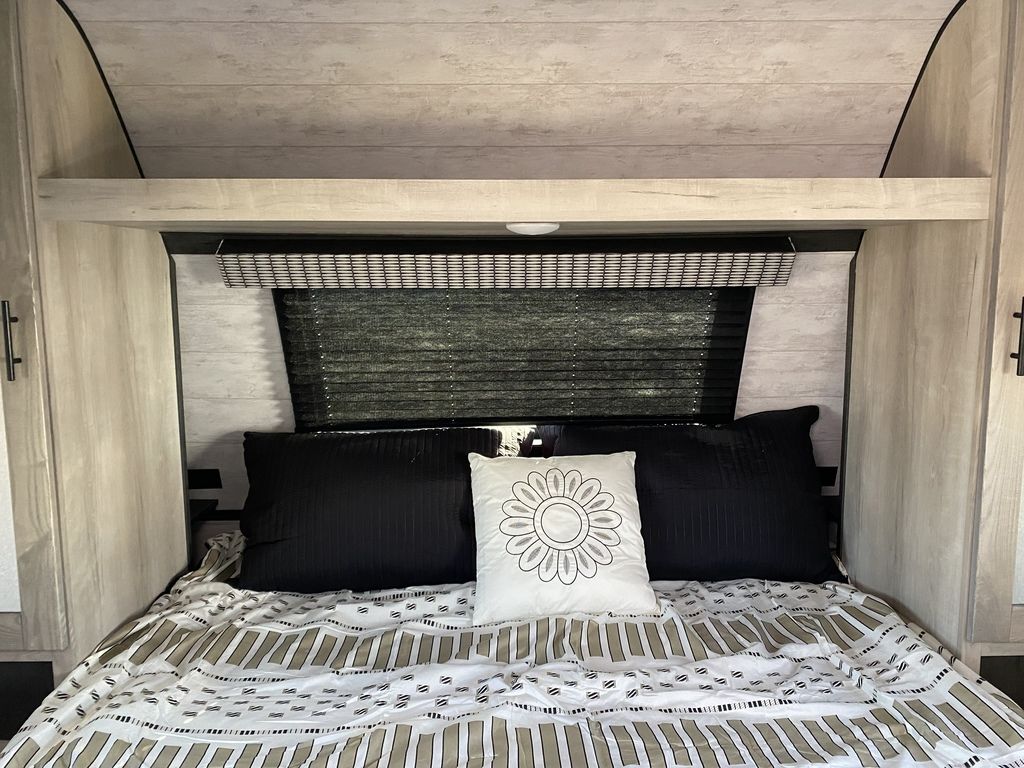 Cozy RV rental bedroom featuring striped bedding, black/white pillows, light wood cabinetry, and window blinds.. KZ KZ CONNECT C241RLK 2022