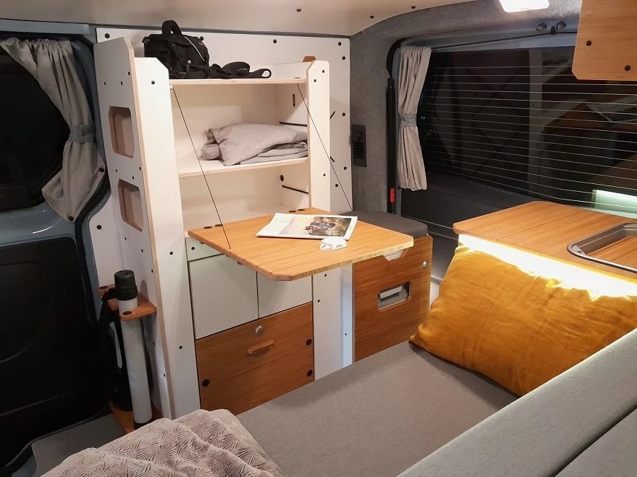 Inside a modern **rv rental**: a compact camper van interior with modular storage, fold-down table, and comfy bed setup.. Renault TRAFIC 2024