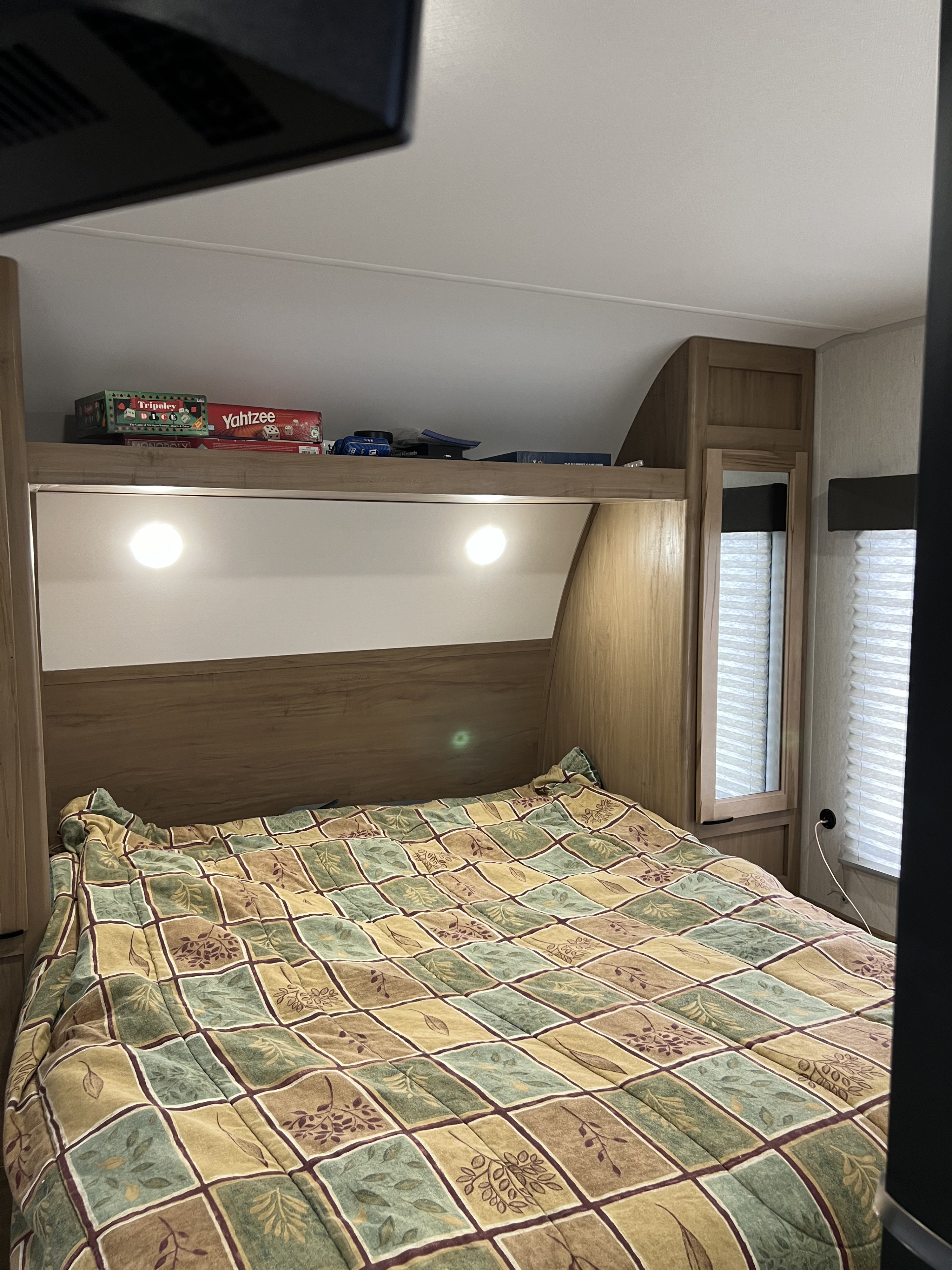 Cozy RV rental bedroom with a comfy bed, overhead shelf storing board games, and ambient lighting.. Forest River Cherokee 282ds 2024