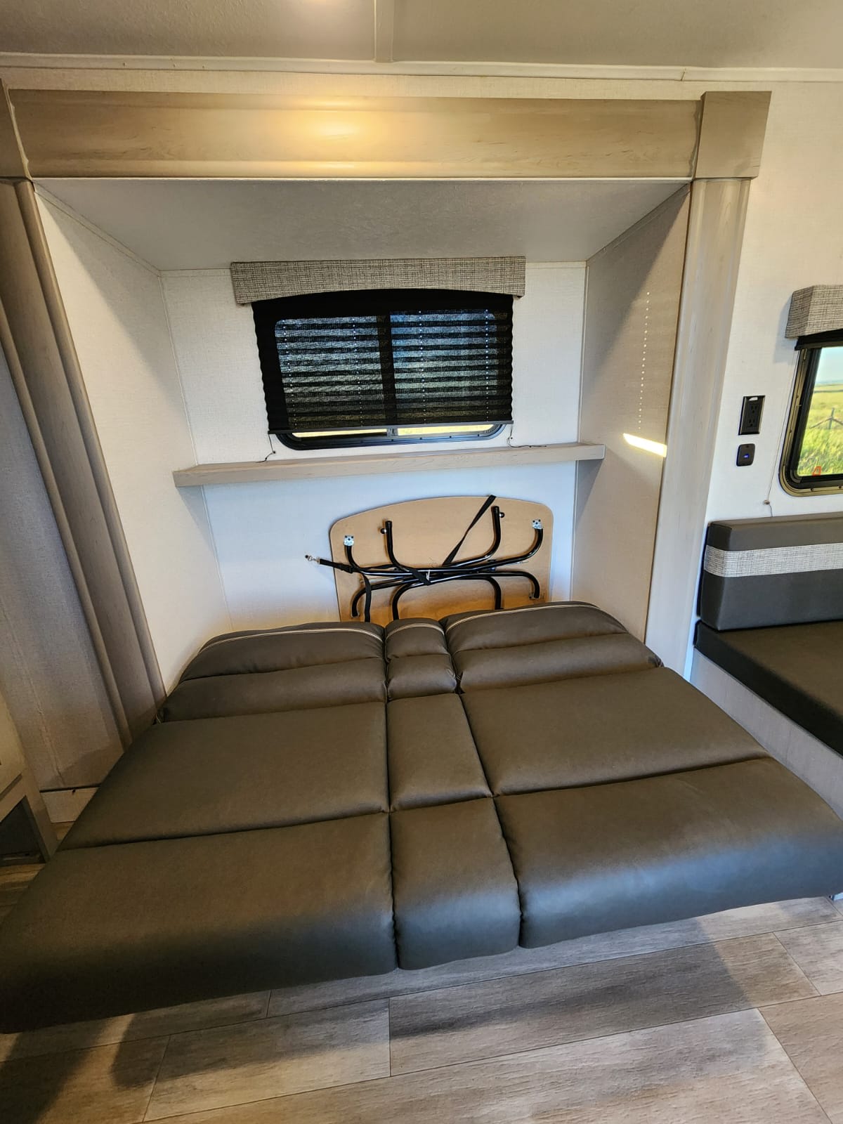 Explore this RV rental interior featuring a comfy convertible bed, window, and a stowable table, ideal for travel.. Forest River Coachmen Classic 2023
