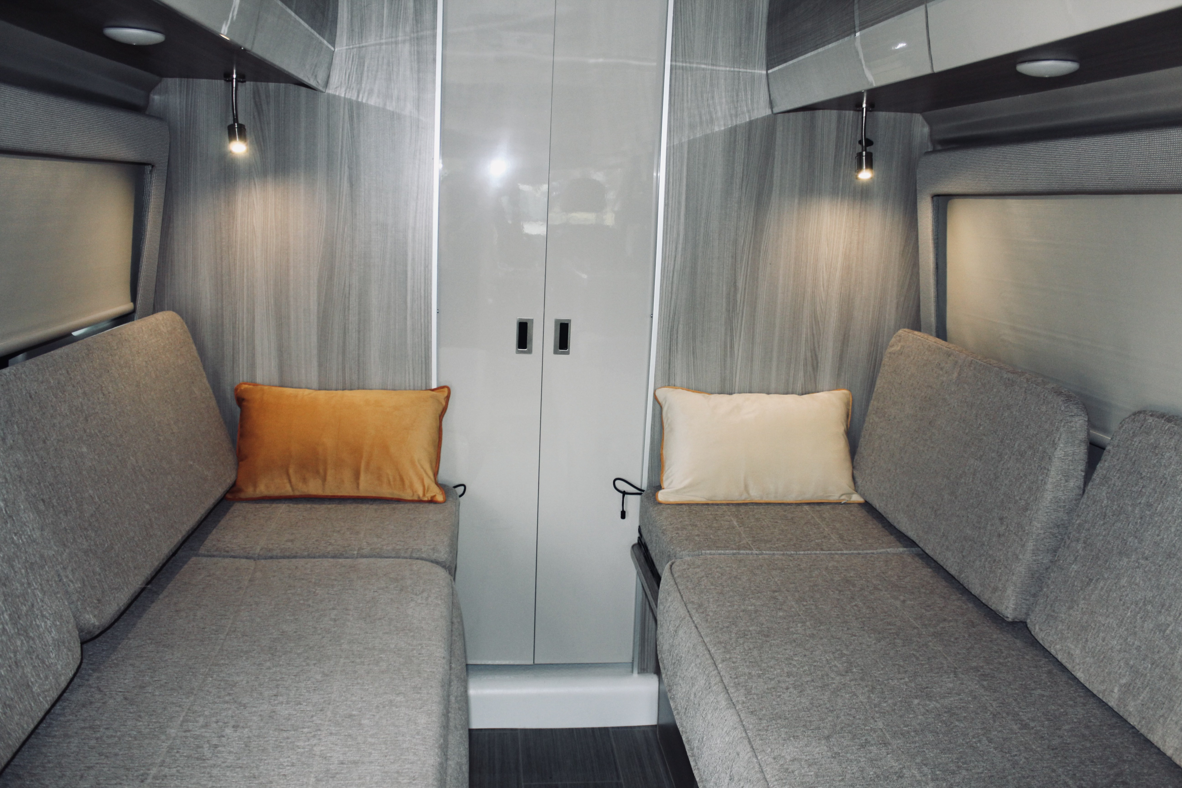 Modern RV rental interior: cozy facing benches with pillows, reading lights, and central storage.. Thor Sequence 2023
