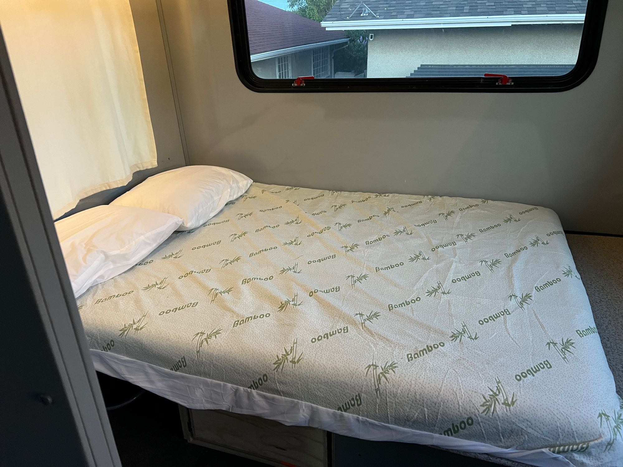 Comfortable RV rental bed with a bamboo mattress cover and window view, ready for travel adventures.. Chevrolet Express shuttle 2014