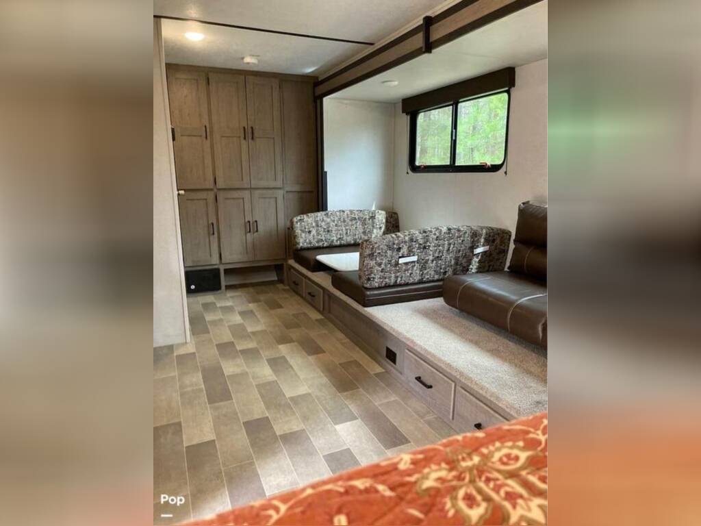 Inside an RV rental, featuring wood-look flooring, built-in cabinets, a convertible dinette, and comfy sofa with storage.. Keystone RV Hideout 2023