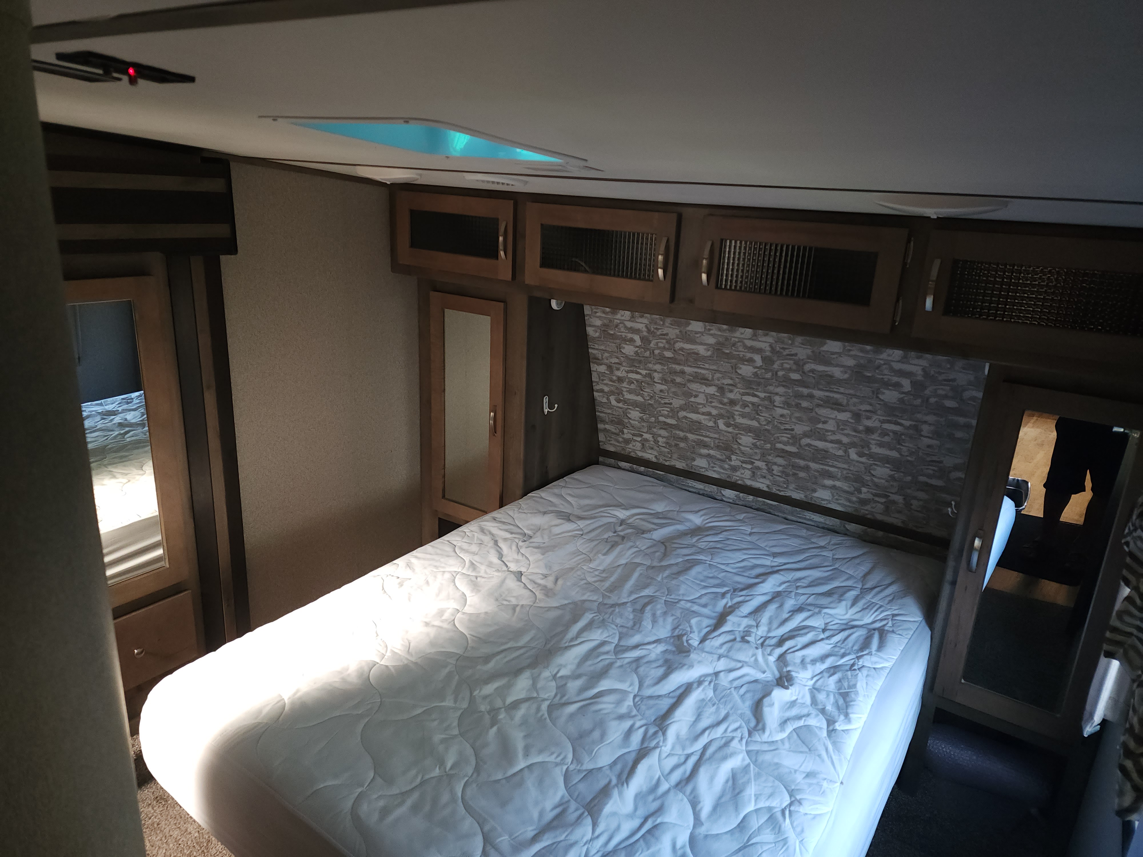 Experience the comfort of an RV rental bedroom: a cozy bed, overhead cabinets, and skylight for a bright interior.. Keystone RV Sprinter Campfire Edition 2019