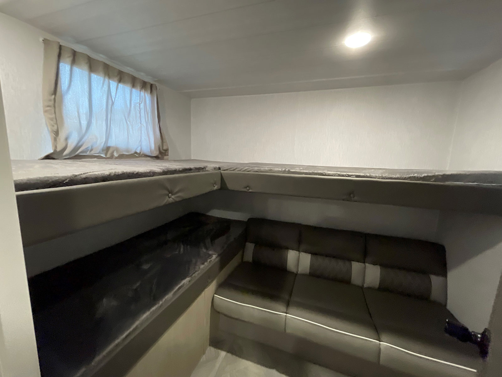 This RV rental offers cozy bunk beds with soft gray bedding and a comfortable dinette area for relaxation, featuring neutral tones.. Forest River Salem Cruise Lite 2021