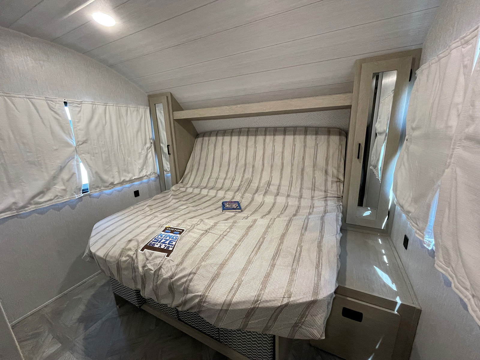 Cozy rv rental bedroom showing a custom king-size bed (66"x78"), light wood storage, and bright windows.. Forest River Salem Cruise Lite 2021