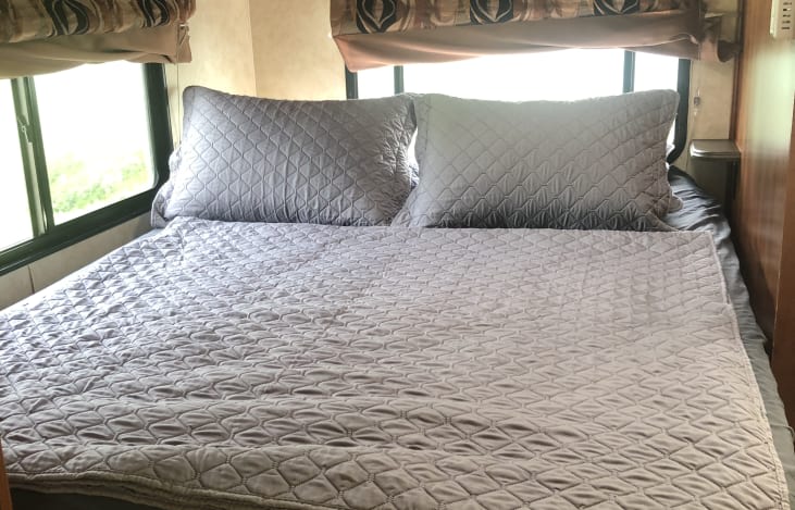 Comfortable RV rental bedroom with a neatly made bed, featuring quilted bedding and pillows, for your travels.. Coachman RV Freelander 2011