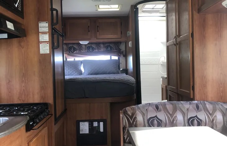 Interior of an RV rental: kitchen, elevated bed, bathroom, and dinette. A functional, compact space.. Coachman RV Freelander 2011