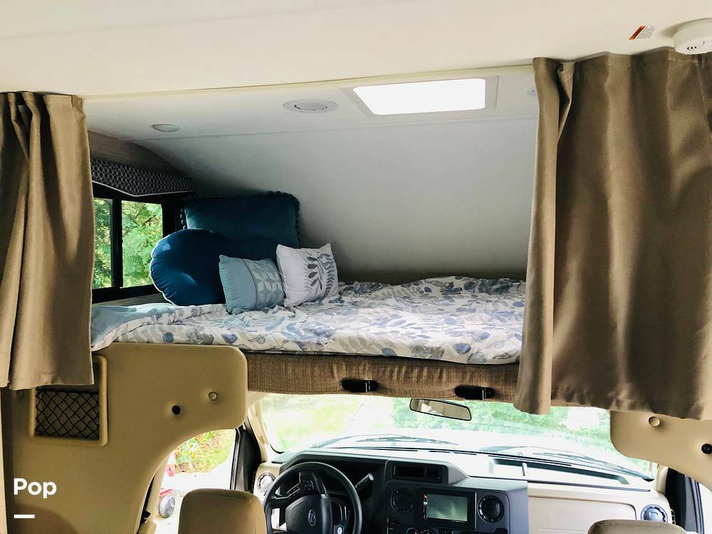 Inside an RV rental: a cozy, decorated cab-over bunk bed with curtains, overlooking the driver's cockpit for your journey.. Thor Motor Coach Chateau 2022