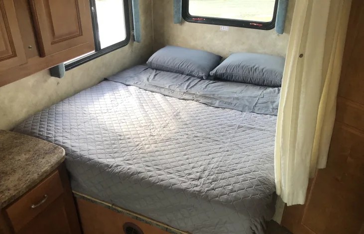 An RV rental bedroom with a comfy bed, two pillows, and windows, ready for a restful night.. Gulf Stream RV 6237 2008