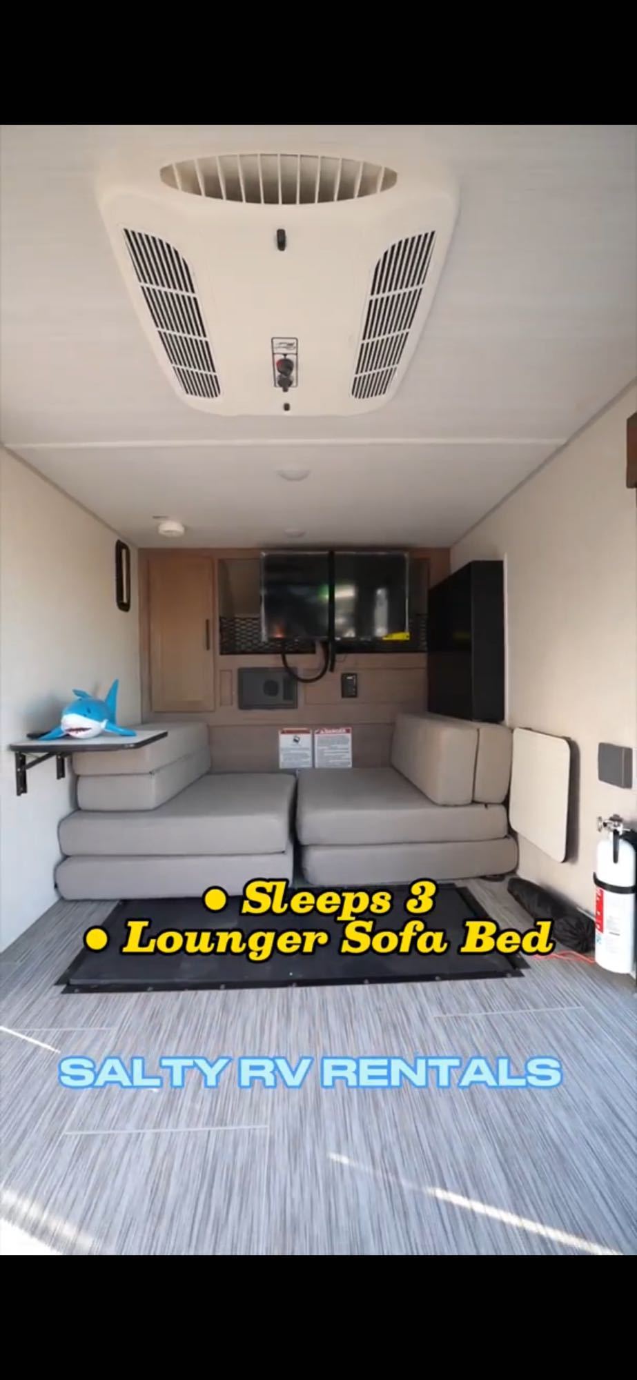 Compact RV rental interior: Lounger sofa bed (sleeps 3), AC unit, and TV for your next adventure.. Forest River NOBO 10.6 2022