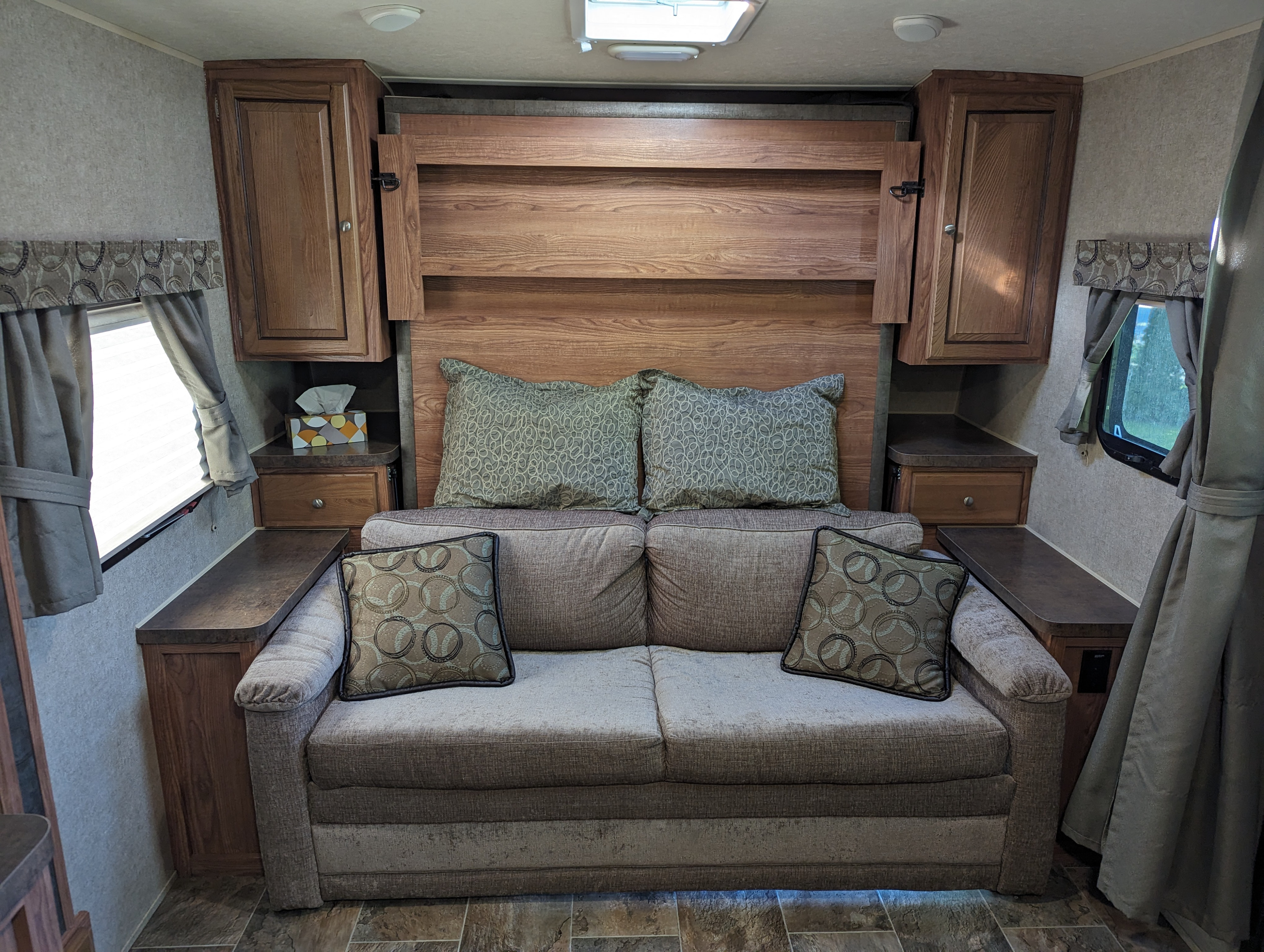 RV rental interior: A practical sofa bed, flanked by wood cabinets & windows, creates a flexible living and sleeping area.. Forest River Rockwood Mini Lite 2015