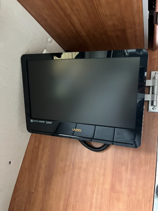 A black Vizio TV is mounted on wood paneling inside an RV rental, offering entertainment on the go.. Roadtrek Roadtrek Class B 2010