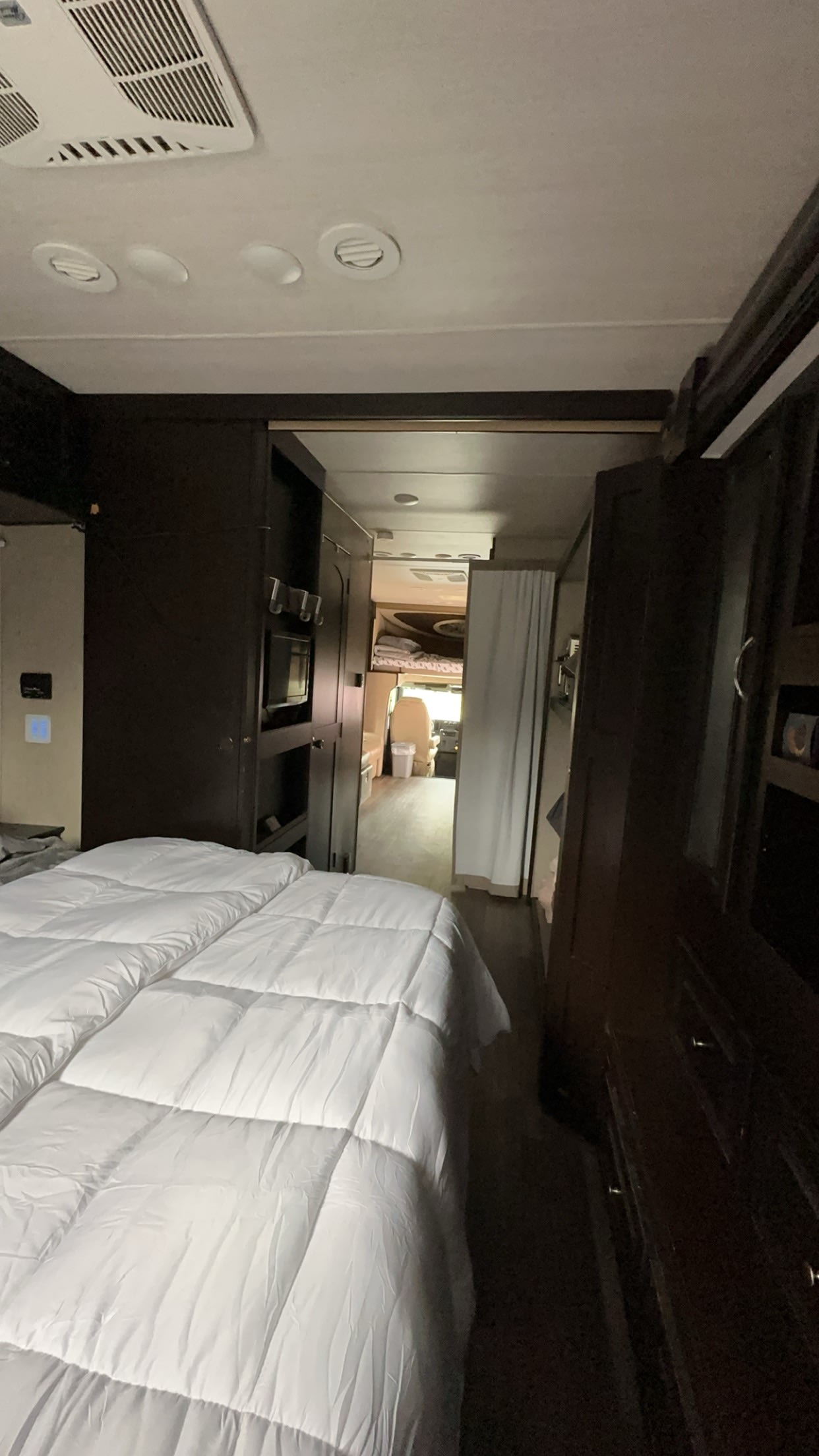 Cozy RV rental interior showcasing a bedroom with white bedding and a hallway leading to the front living area.. Nexus RV Ghost 2020