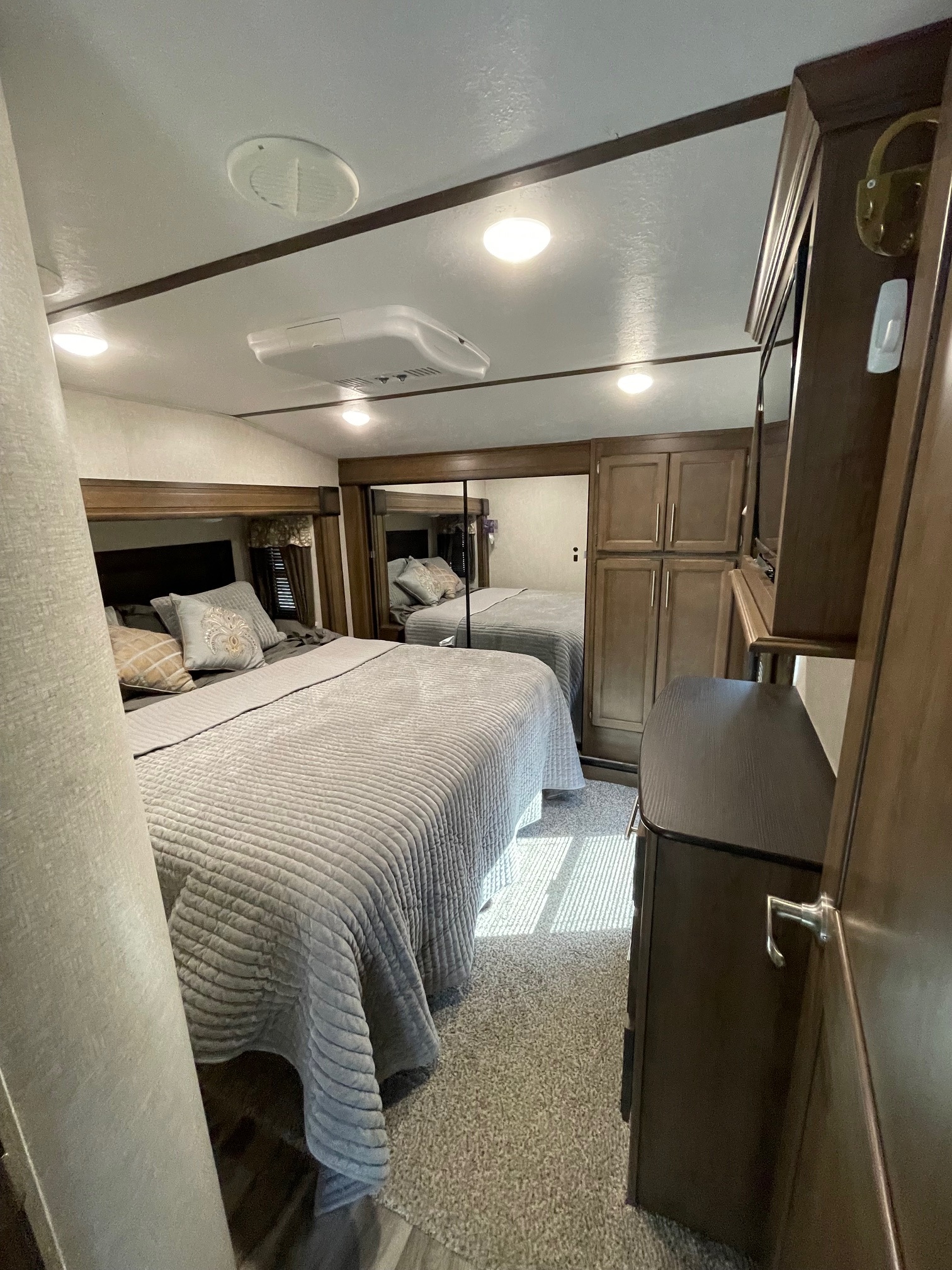 Spacious RV rental bedroom with comfy bed, mirrored wardrobe, dresser, and TV, offering home-like comfort on the go.. Keystone RV Cougar 2019