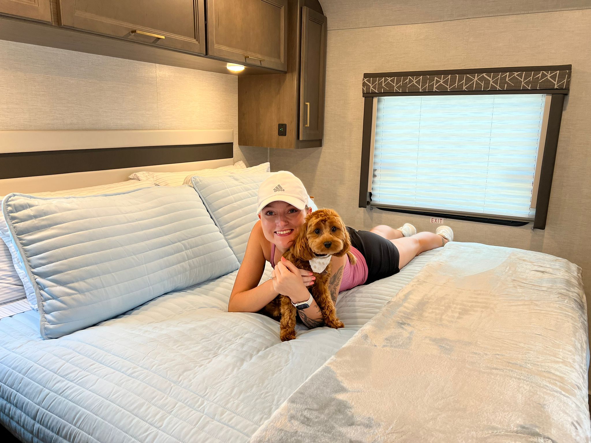 Pet-friendly RV rental comfort! A happy woman and her dog lounge on the bed in a modern RV interior.. Thor Motor Coach A.C.E 2024