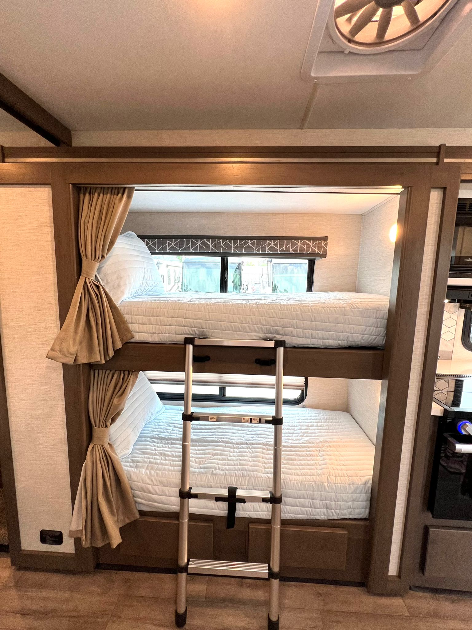 Inside an RV rental: two cozy bunk beds with light blue bedding and a ladder, perfect for family travel.. Thor Motor Coach A.C.E 2024