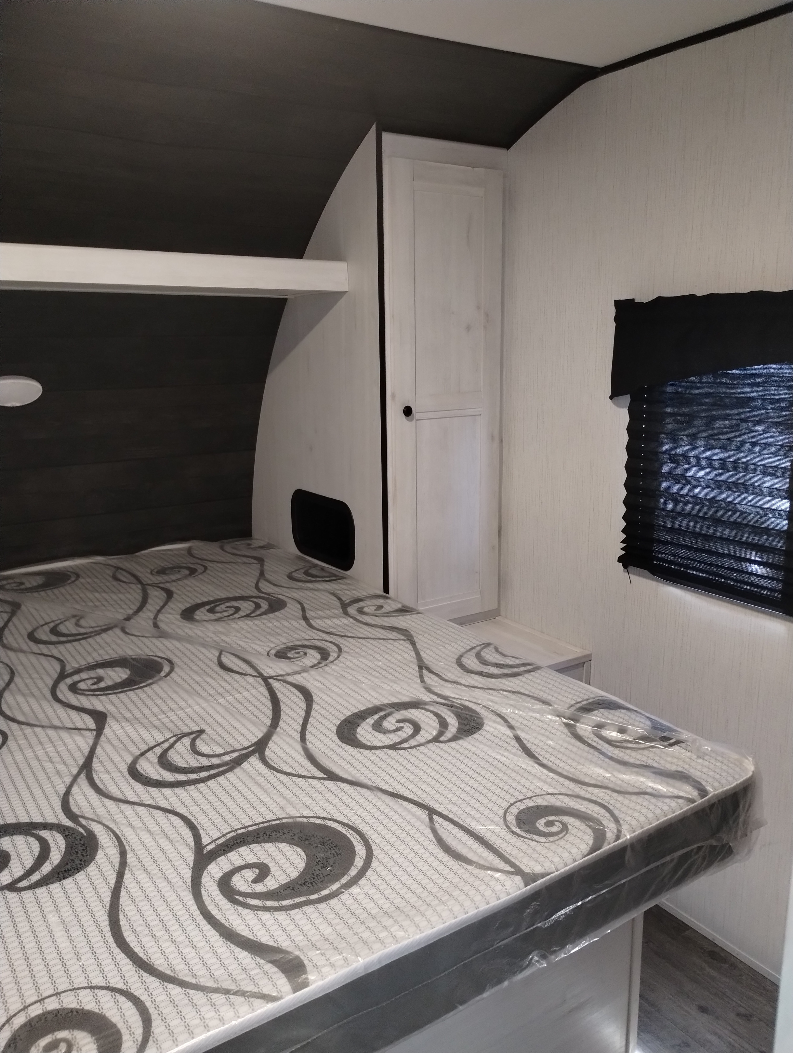 RV rental bedroom featuring a patterned mattress in plastic, built-in storage, and a window with dark blinds.. Heartland RVs Trail Runner 2022