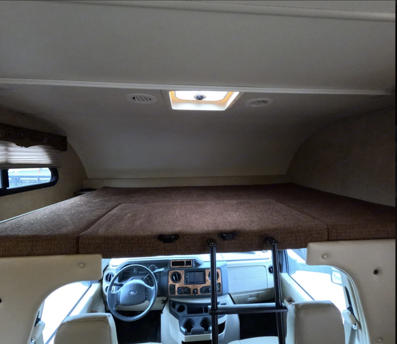 Cozy overhead bunk bed in an RV rental, offering comfortable sleeping space above the driver's cab.. Thor Four Winds 2016