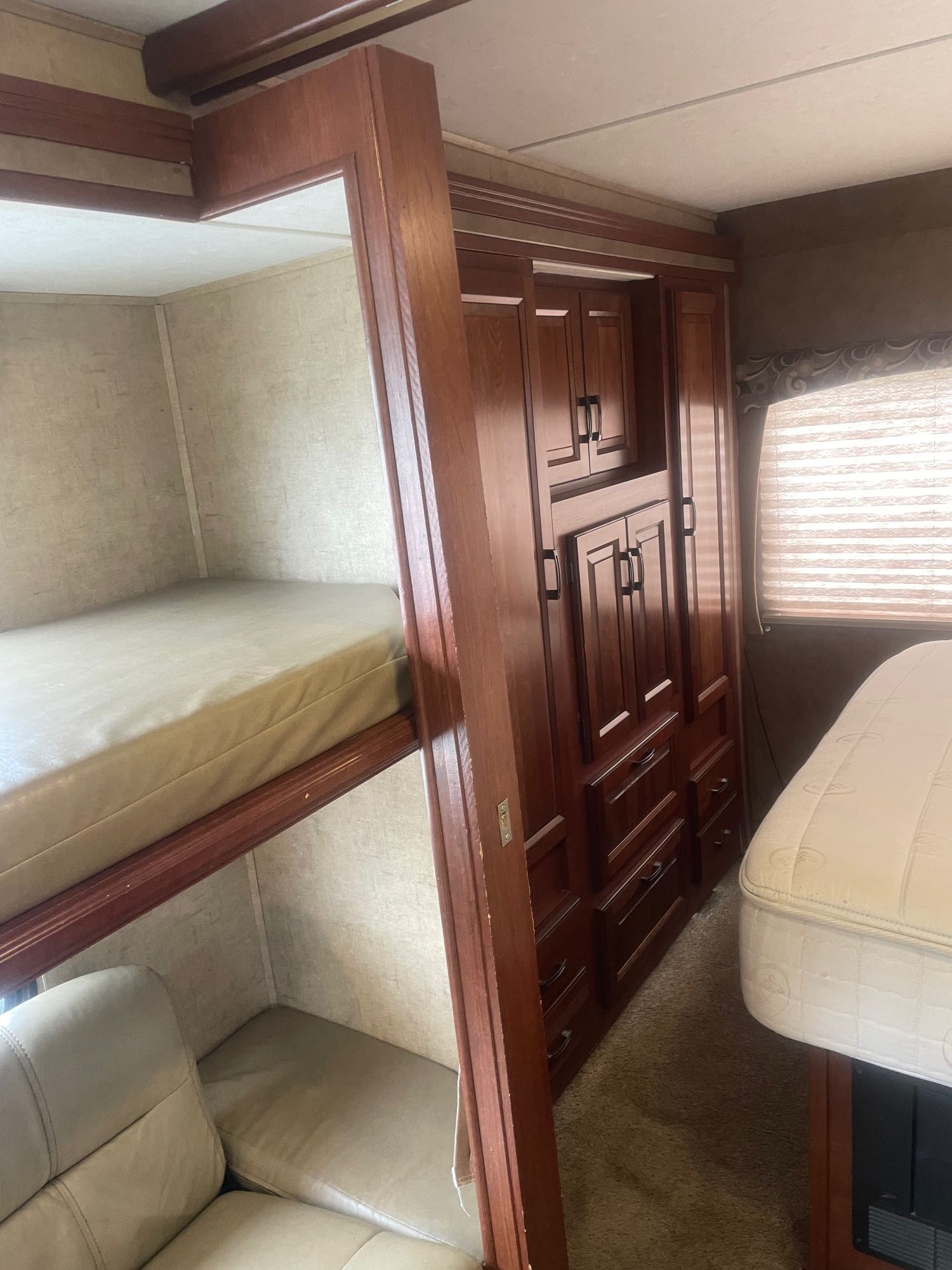 RV rental interior: practical bedroom featuring bunk beds, extensive built-in wooden storage, and a main bed.. Forest River Sunseeker 2016