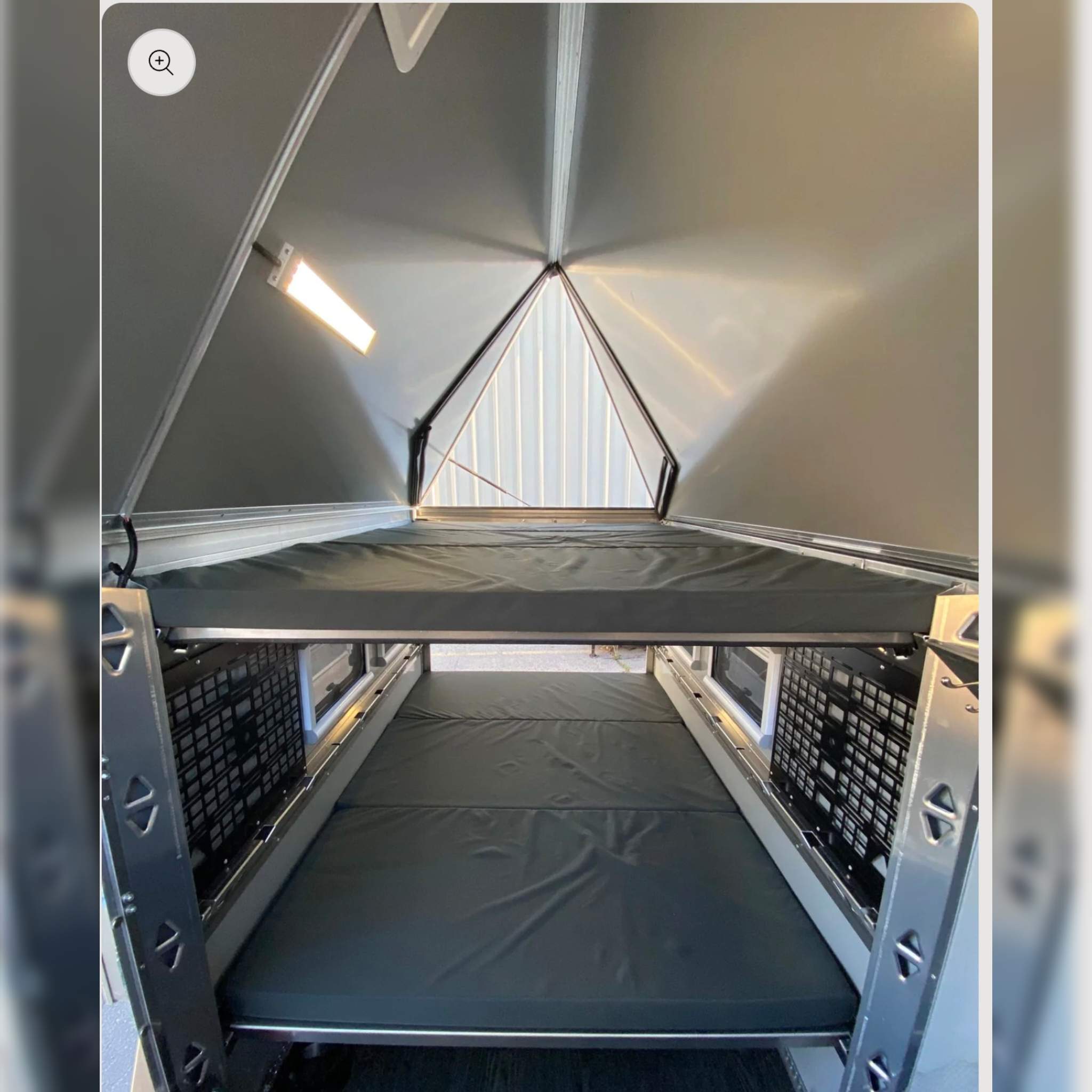 RV rental interior: Two gray mattresses form bunk beds on metal frames. A pop-top roof expands the compact sleeping area.. Other Other 2023