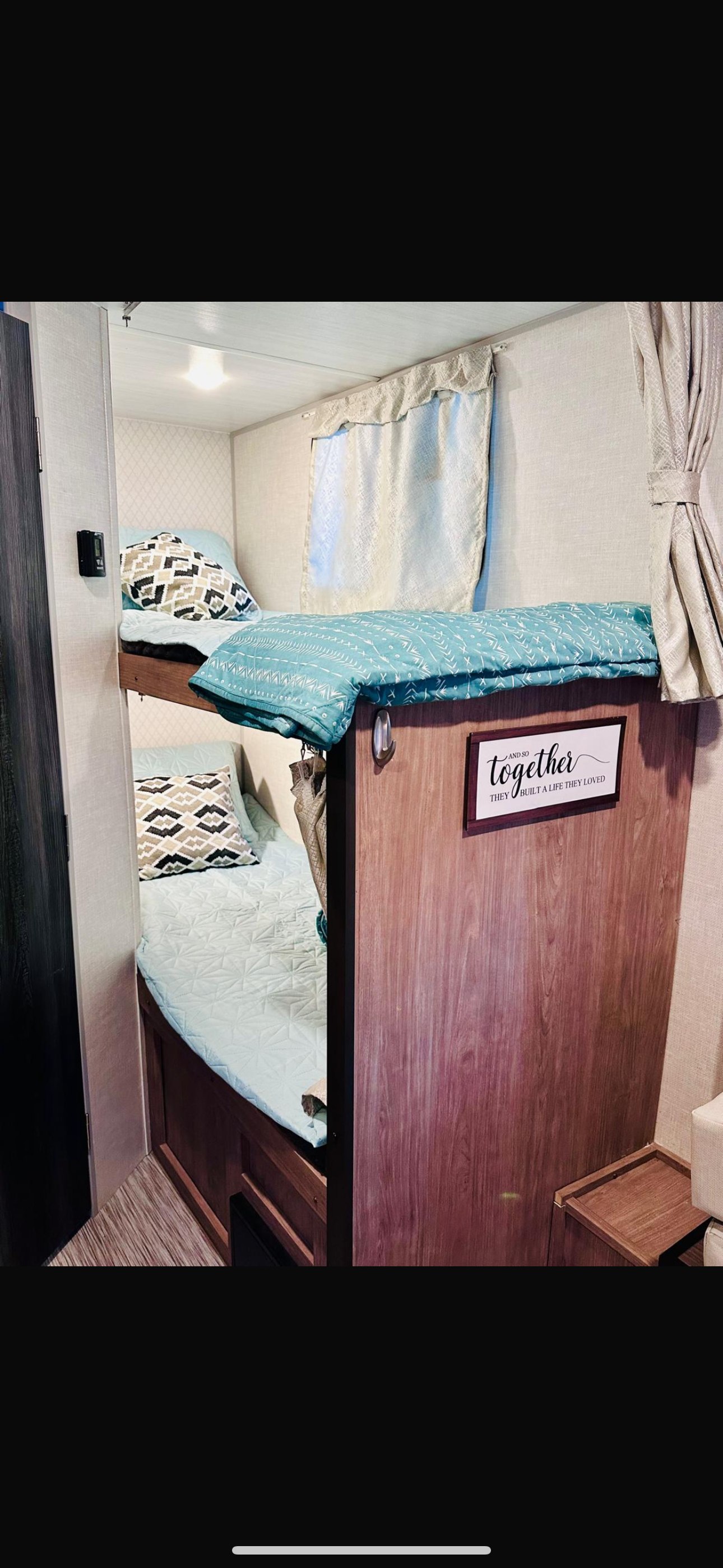 Cozy RV rental interior showing bunk beds with light blue bedding and patterned pillows. A welcoming sleep area.. No Boundaries 19.8 2021