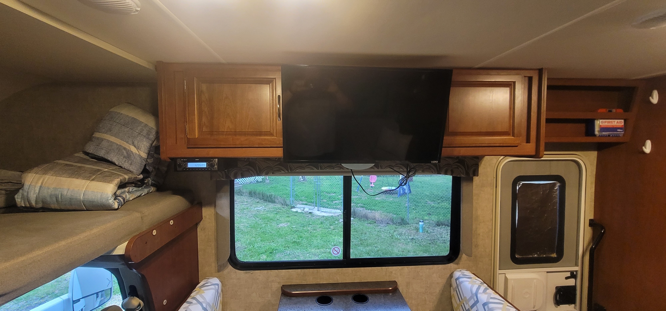 Experience comfort in this rv rental. Interior view with a cab-over bed, TV, storage cabinets, and a window to the outside.. Winnebago Minnie Winnie 2016
