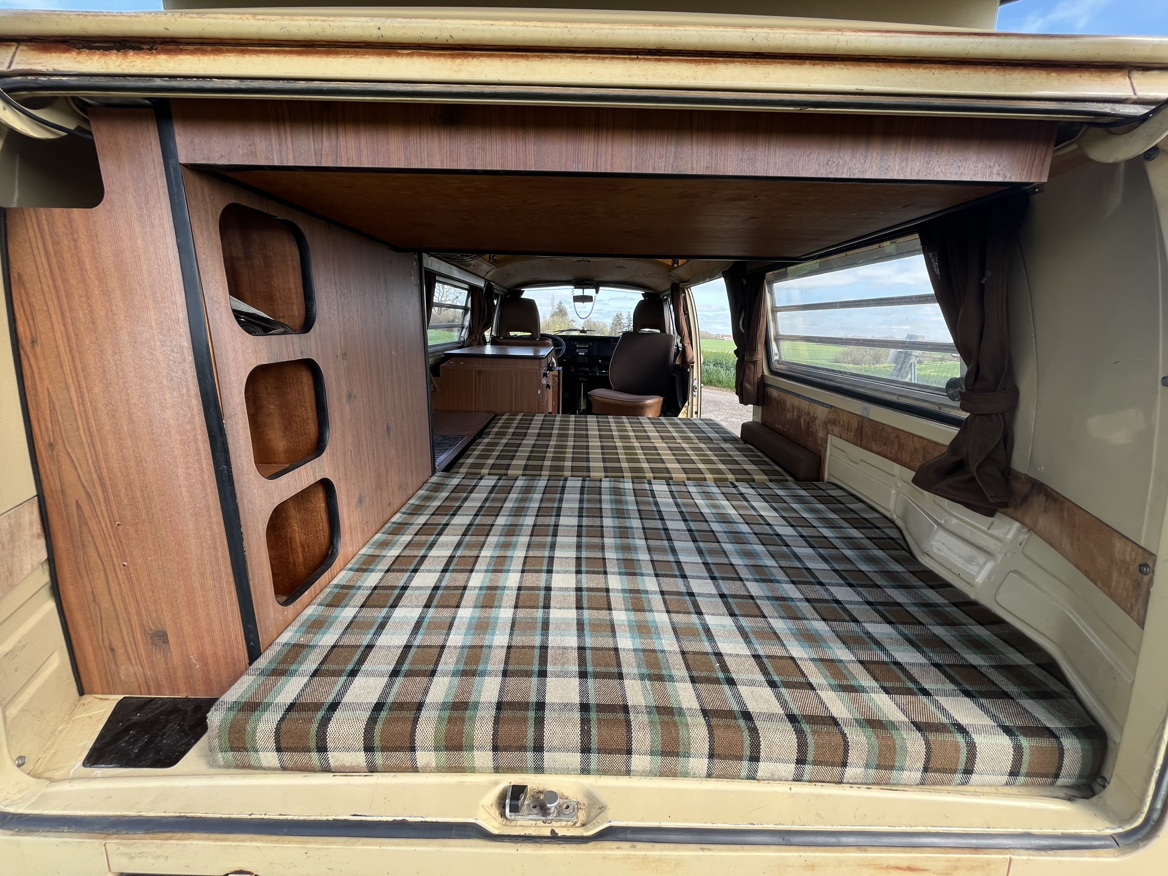 Step inside this vintage camper van for your next RV rental. Features a cozy plaid bed, wood interior, and functional storage.. Volkswagen westfalia 1978