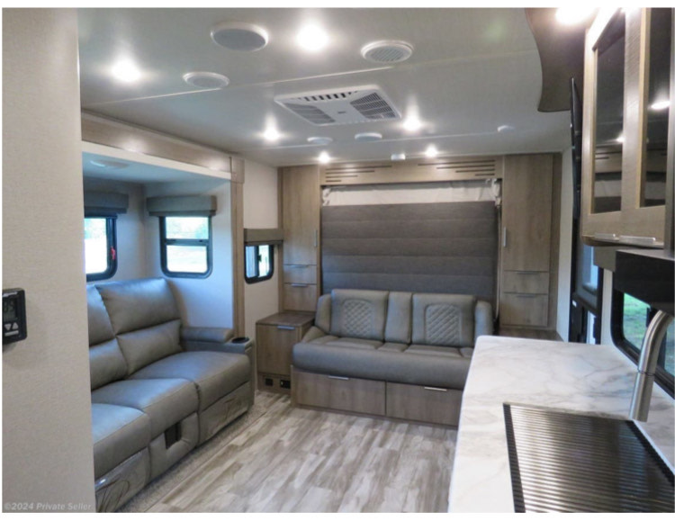 Spacious, modern RV rental interior with comfy sofas, convertible bed area, and kitchen counter for travel comfort.. Grand Design Imagine XLS 2021