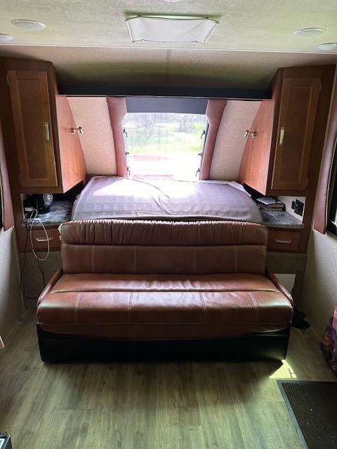 RV rental interior showcasing a comfortable bed, brown leather sofa, and built-in wooden cabinets. Perfect camper setup.. Lance Manufacturing Lance Manufacturing Trailer 2020