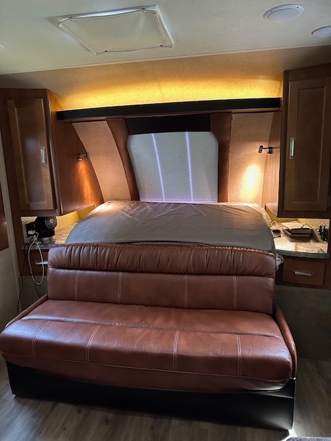 Cozy RV rental interior with a comfortable bed, brown leather sofa, and ample storage, perfect for travel.. Lance Manufacturing Lance Manufacturing Trailer 2020