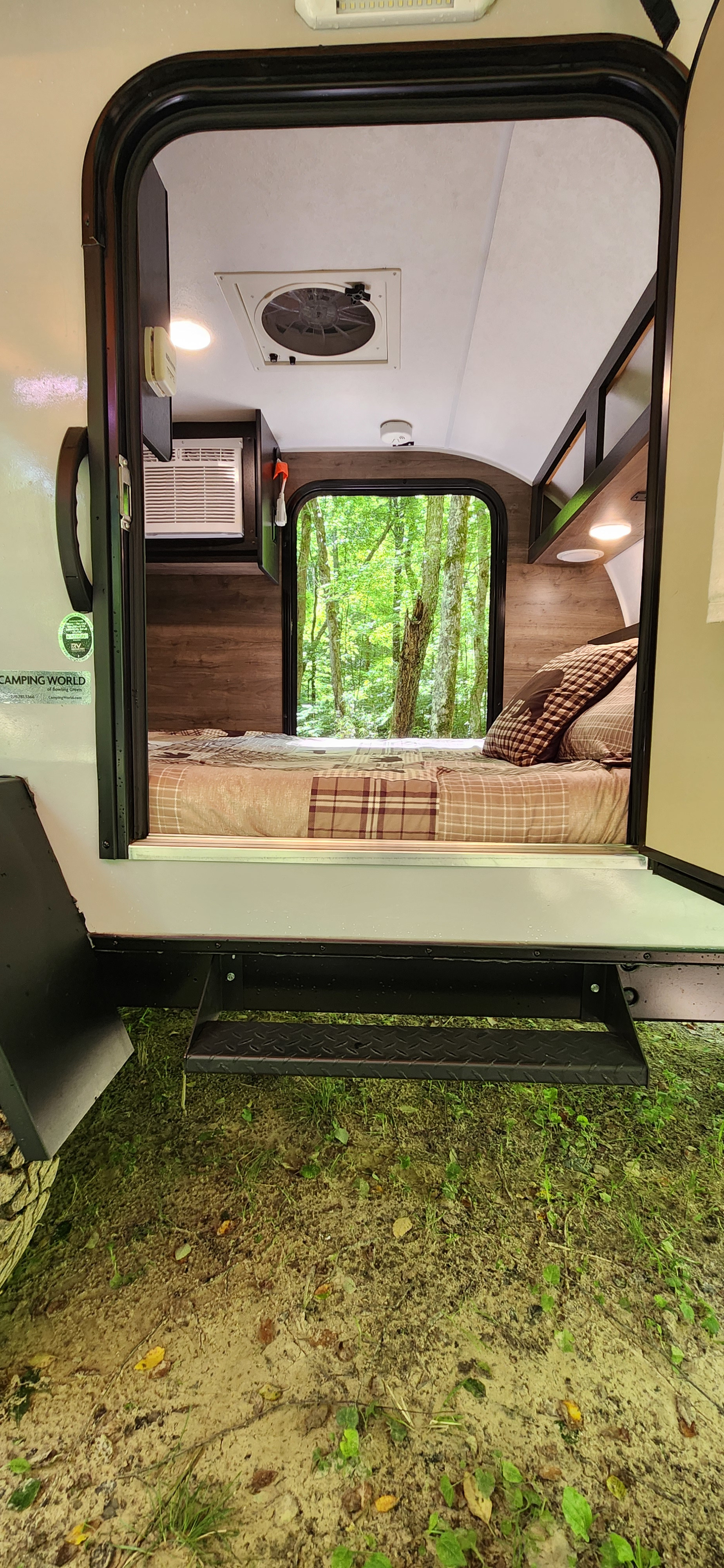 Cozy RV rental interior offers a serene forest view, steps leading to nature. Perfect for a peaceful camping trip.. Braxton Creek Free Solo 2022