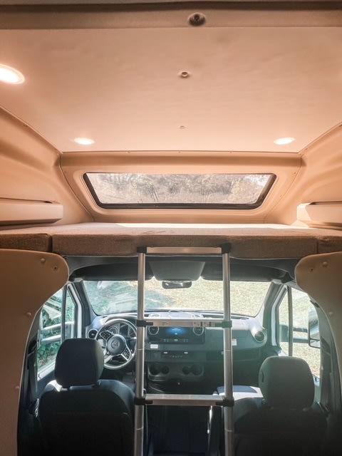 Spacious RV rental interior: Ladder to cozy cab-over bunk, overlooking the cockpit. Ideal for road trip adventures.. Entegra Coach Qwest 24L 2024