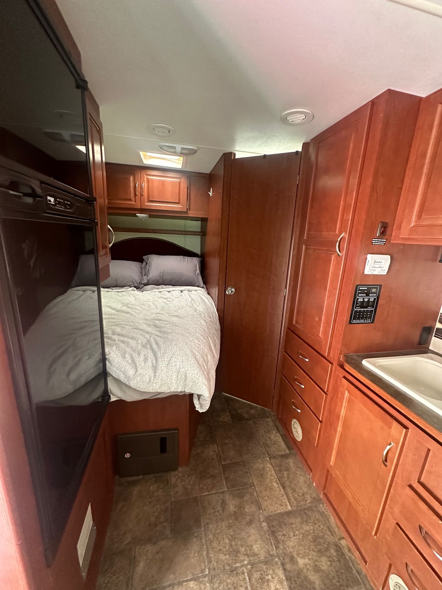 Inside this RV rental: a comfortable bed in the bedroom, a compact kitchen with a sink, and warm wood cabinetry.. Winnebago minnie winnie 2013