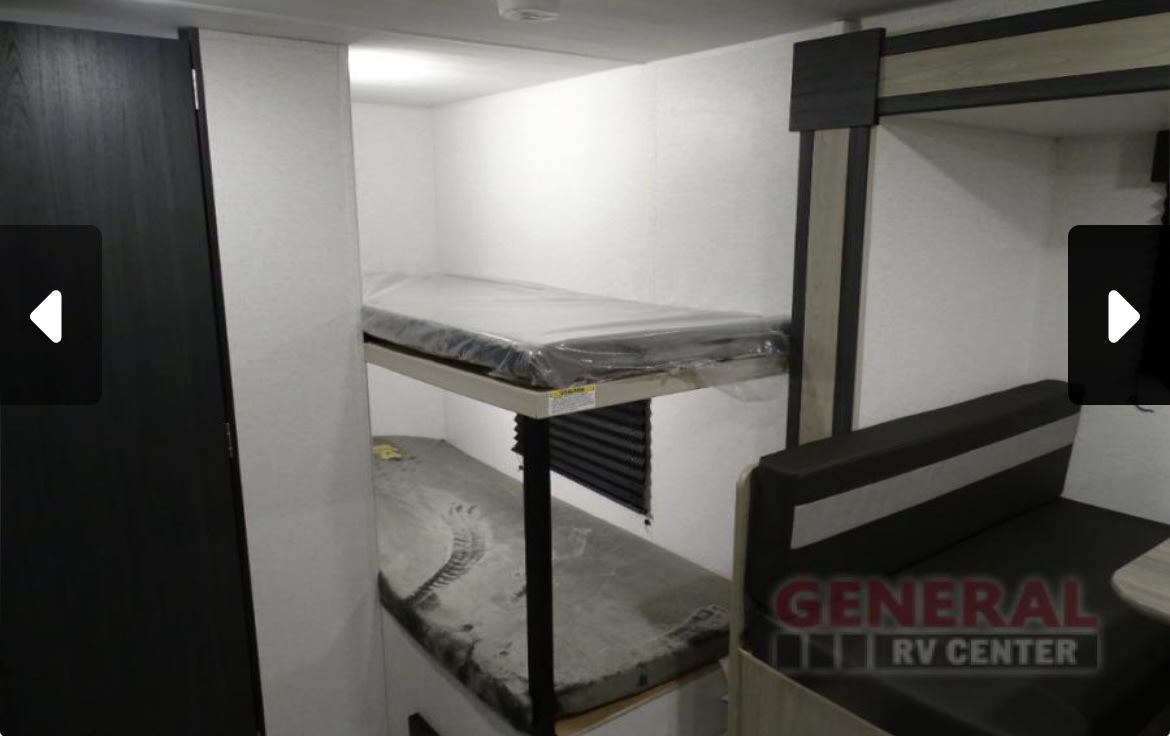 This RV rental interior features bunk beds for sleeping and a dinette area for dining, ready for your next adventure.. Keystone RV Springdale 2024