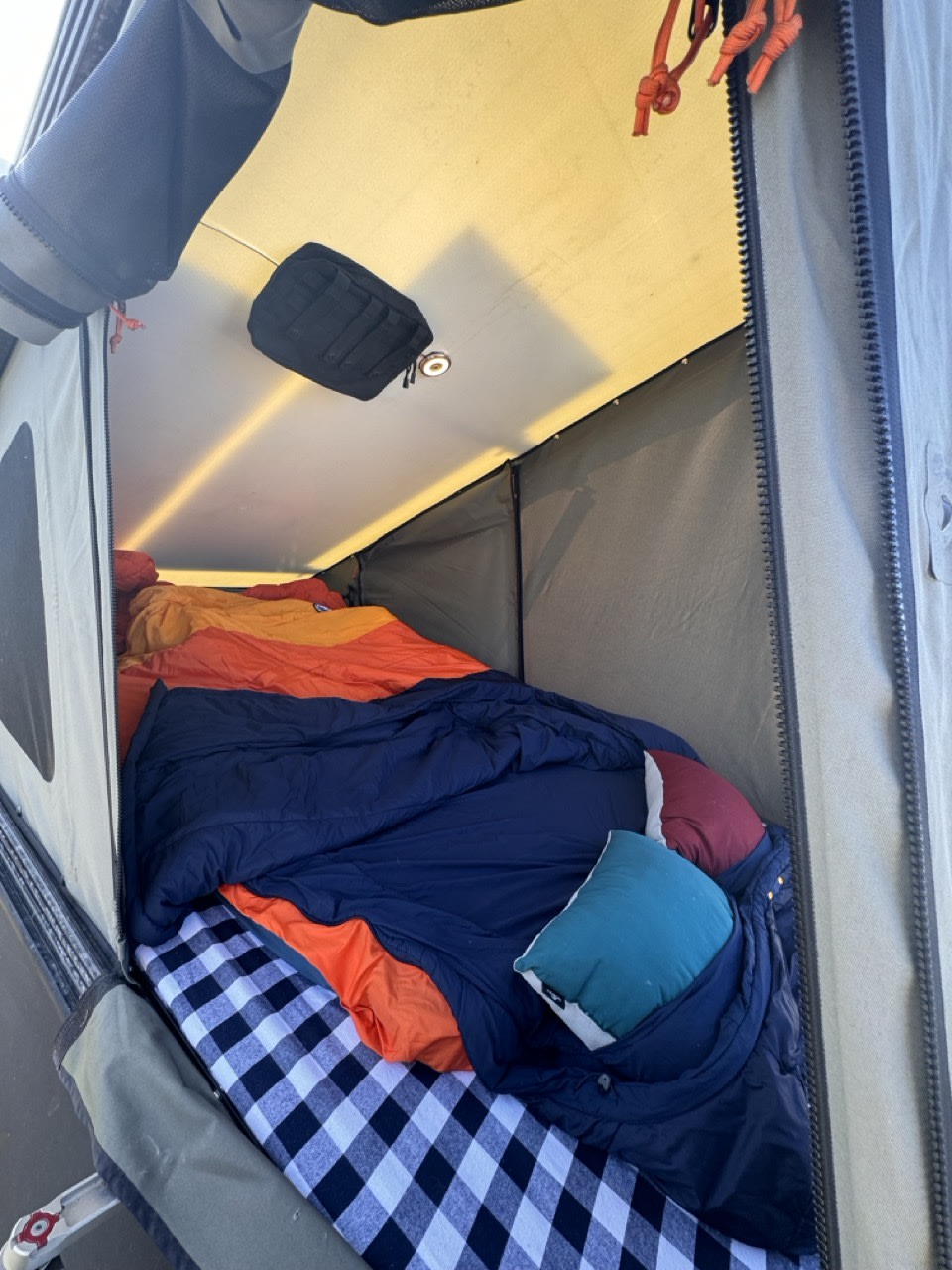 Inside an RV rental camping tent: a cozy bed with colorful blankets & pillows. Ready for adventure!. Toyota Tacoma - GoFastCamper 2007