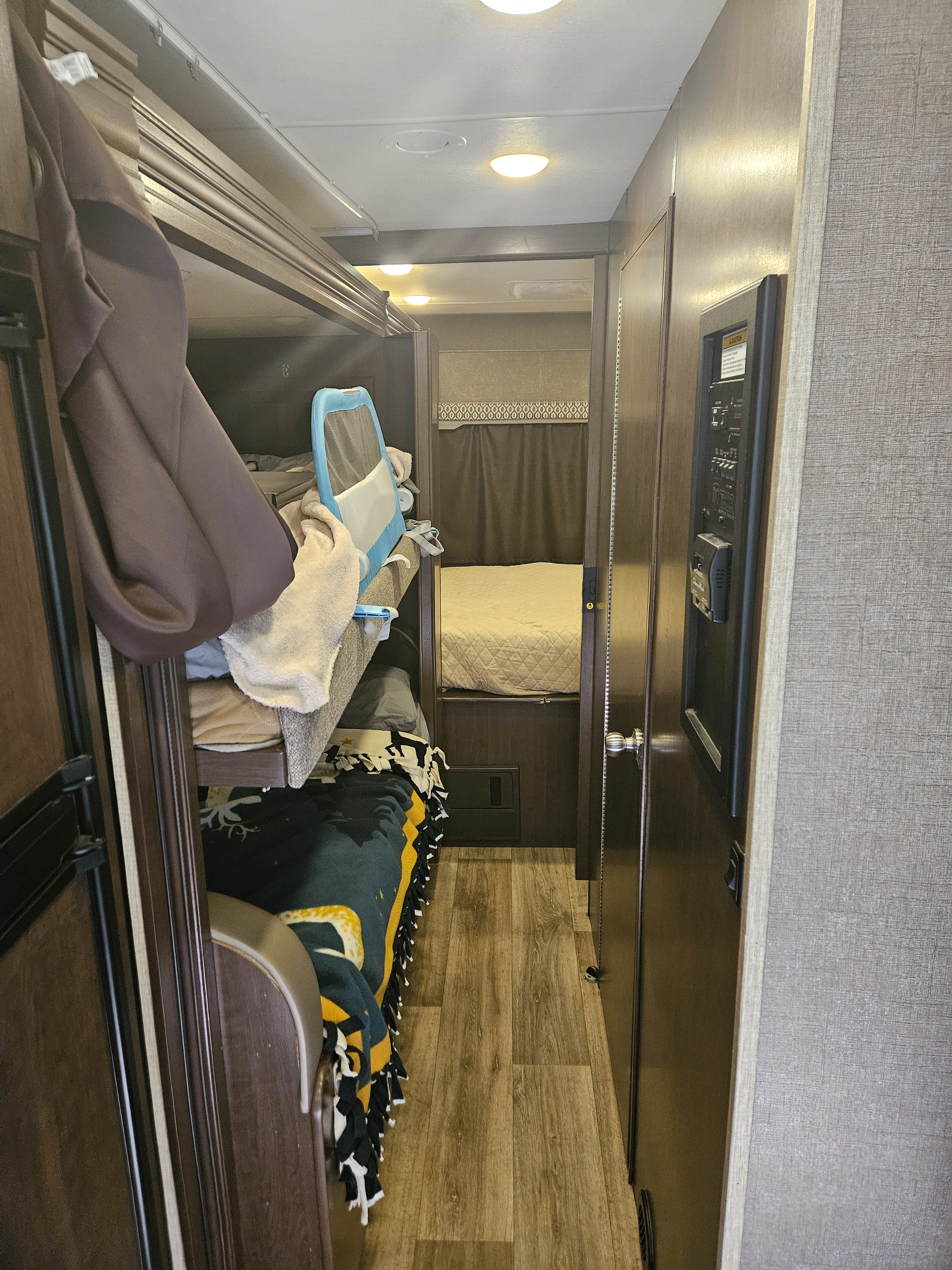 RV rental showing bunk beds on left, a central hall leading to a rear bedroom, and system controls on right.. Thor Freedom Elite 2018