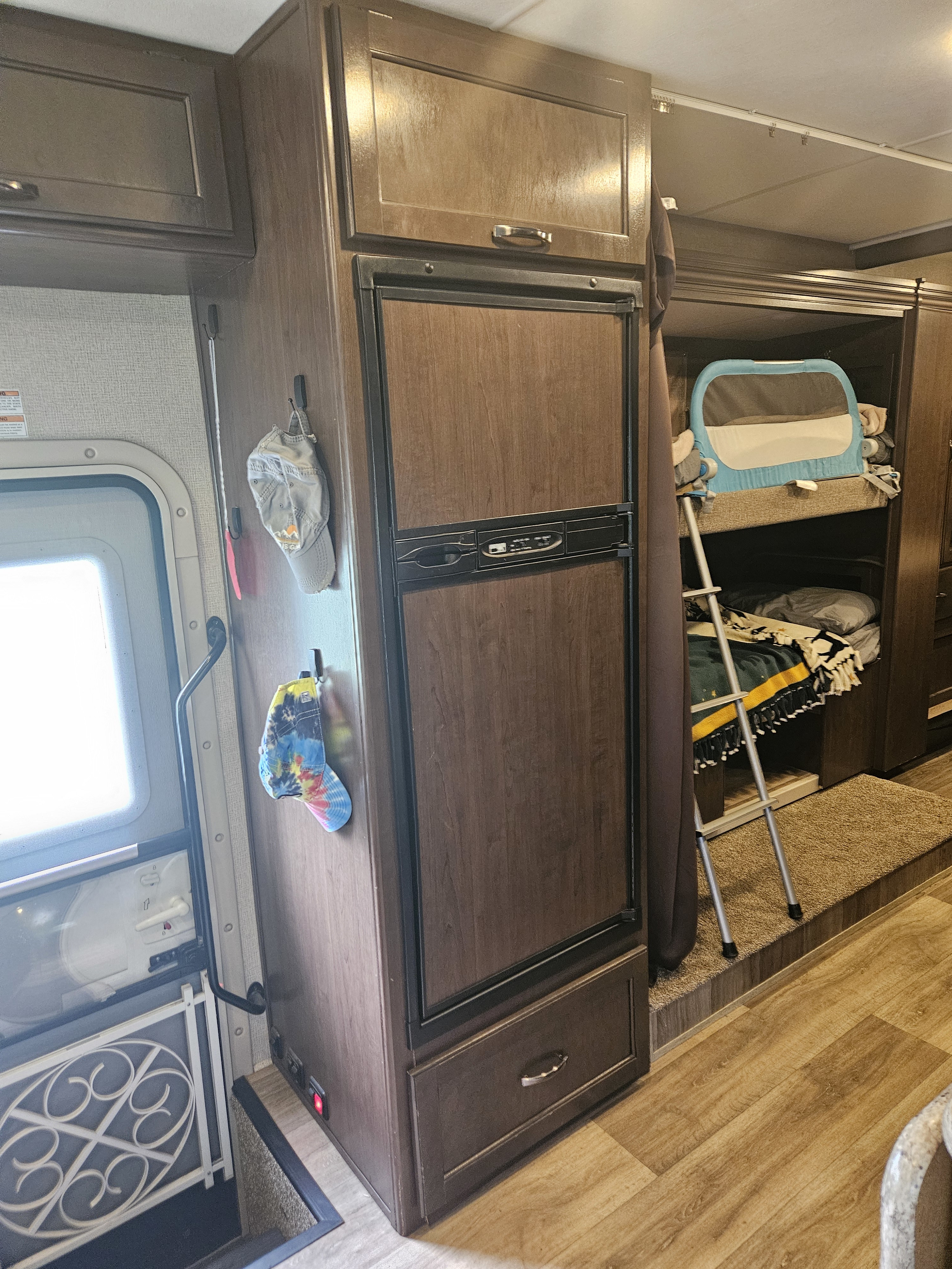 RV rental interior showcasing a large refrigerator, cozy bunk beds with safety rail, and main entrance. Ideal for family trips.. Thor Freedom Elite 2018