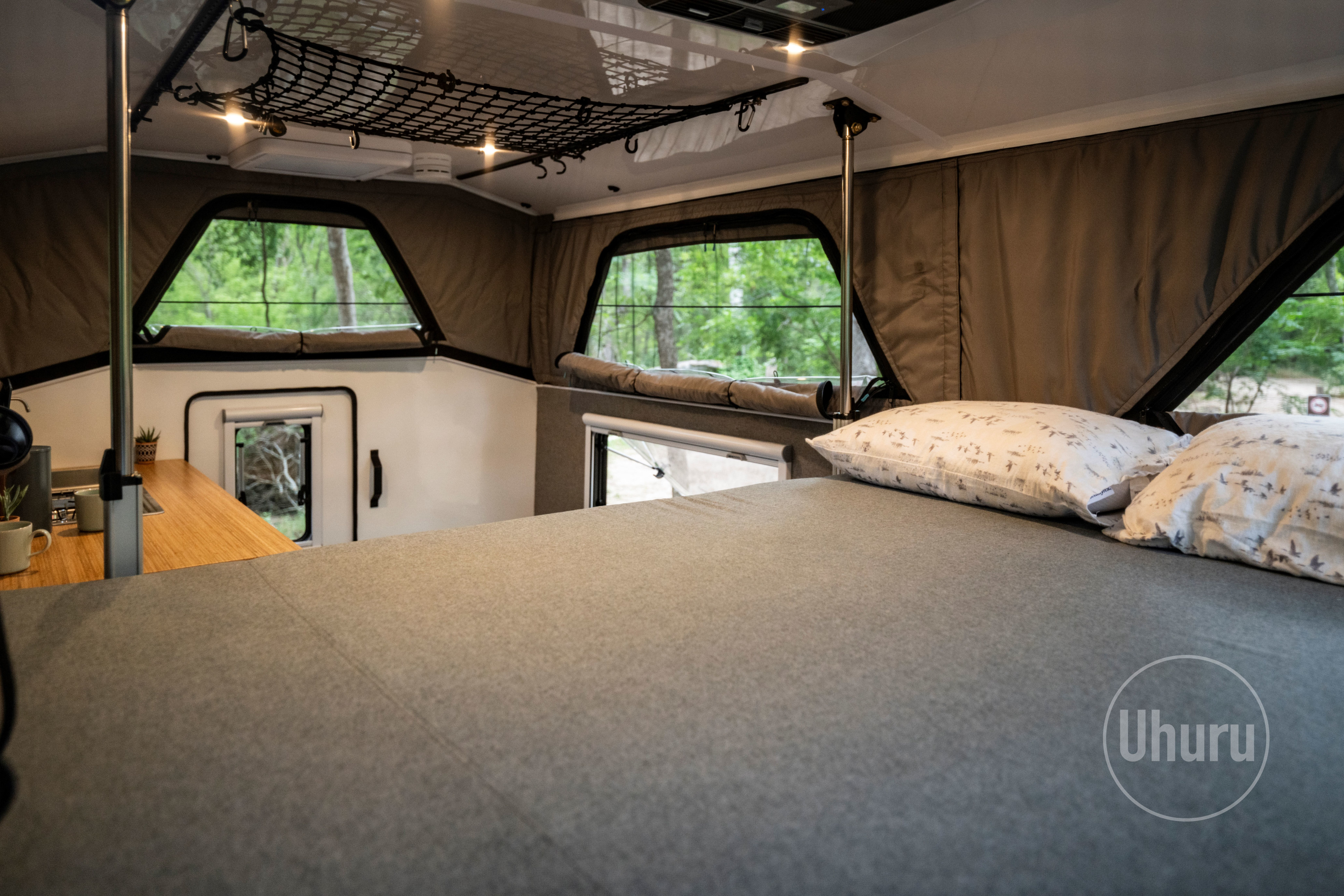 Explore the spacious interior of this RV rental, featuring a large bed, kitchen area, and panoramic windows for forest views.. Ford F350 2024