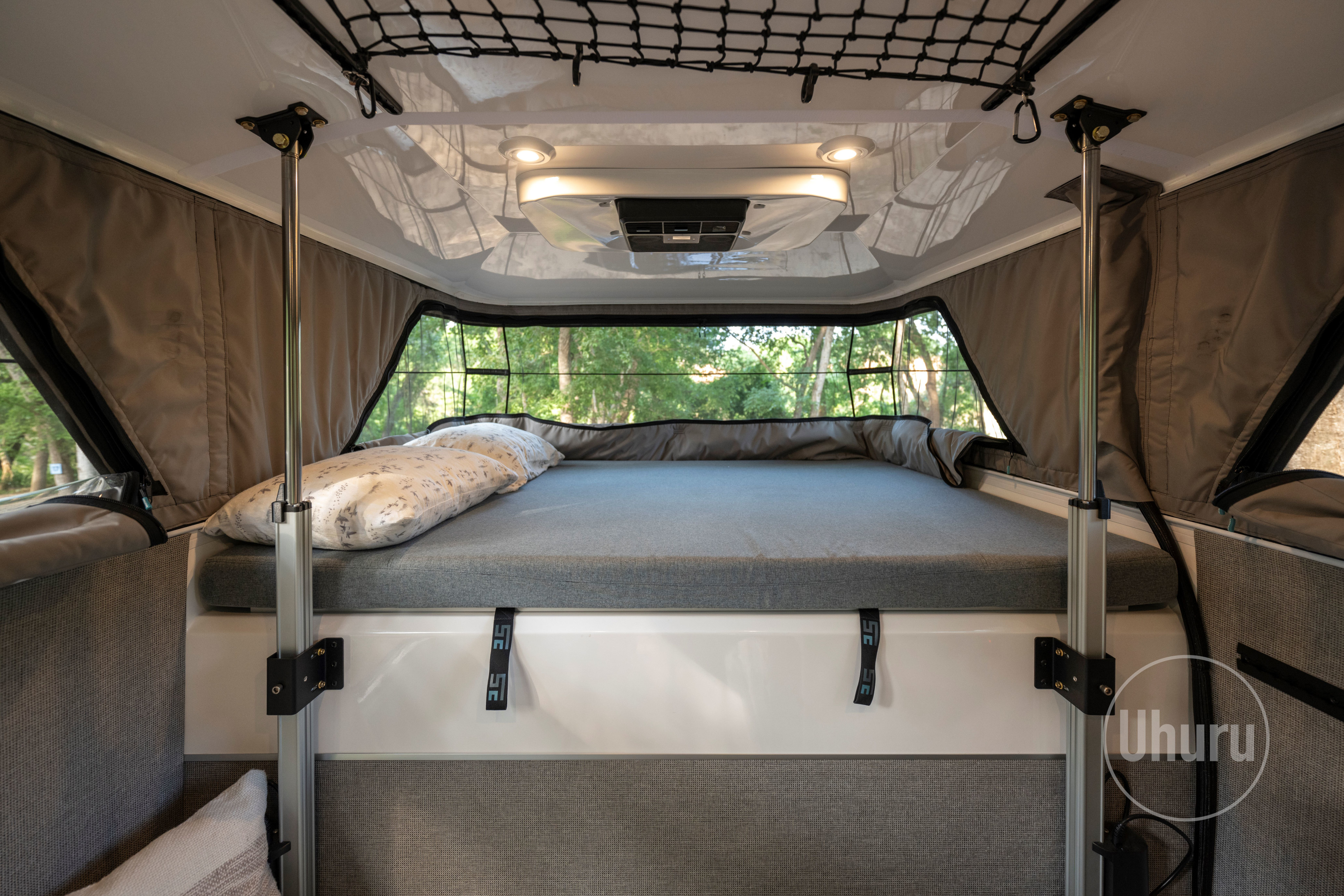 Comfortable RV rental bedroom with large panoramic windows, a comfy bed, and soft lighting, ideal for glamping adventures.. Ford F350 2024