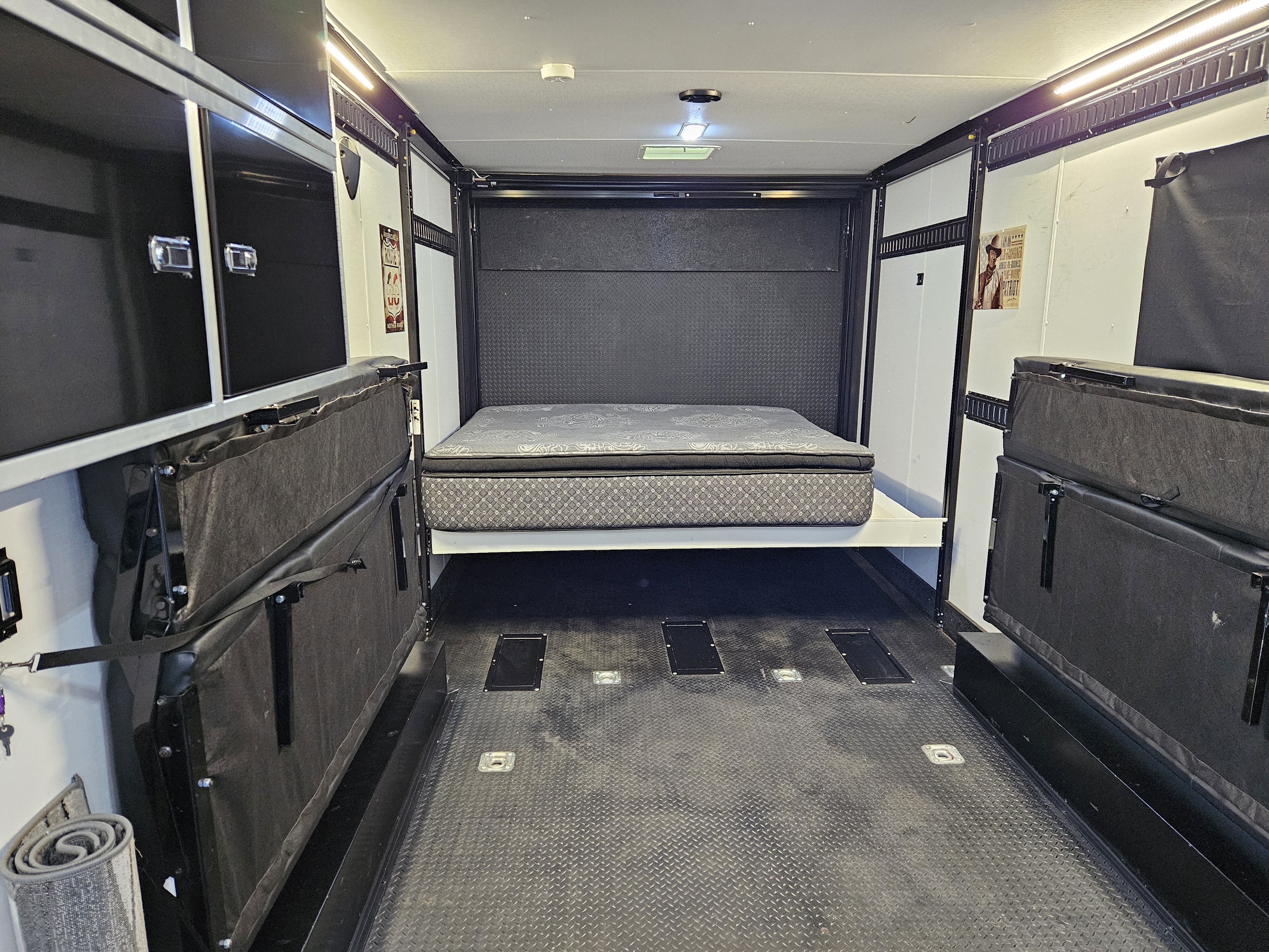 RV rental: Toy hauler interior with a lowered bed at the rear, modular seating folded against the walls.. Stealth Nomad 2021