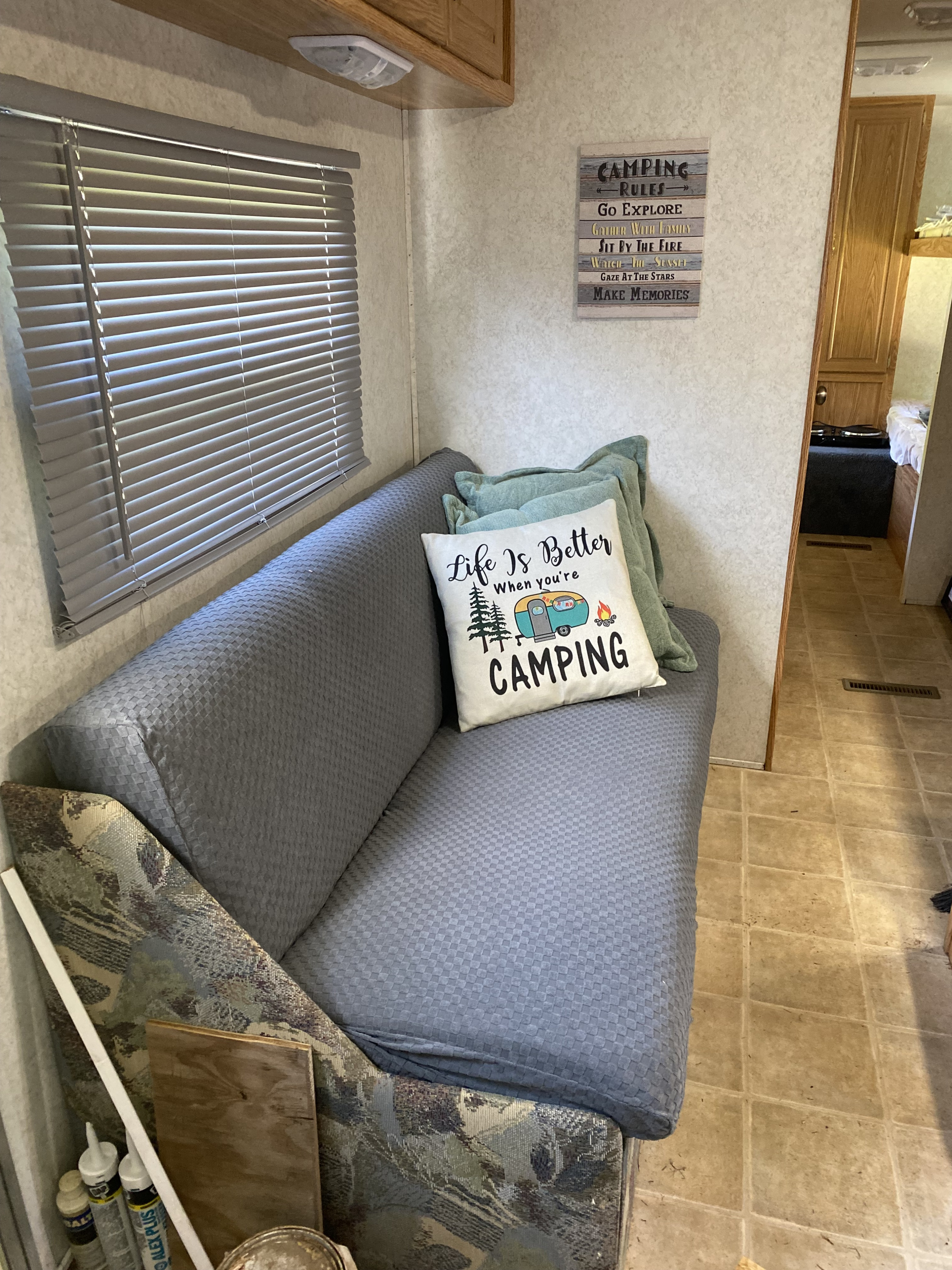 RV rental living area with a cozy sofa, window blinds, and charming camping decor. Perfect for your next road trip adventure.. Dutchmen Lite 2003