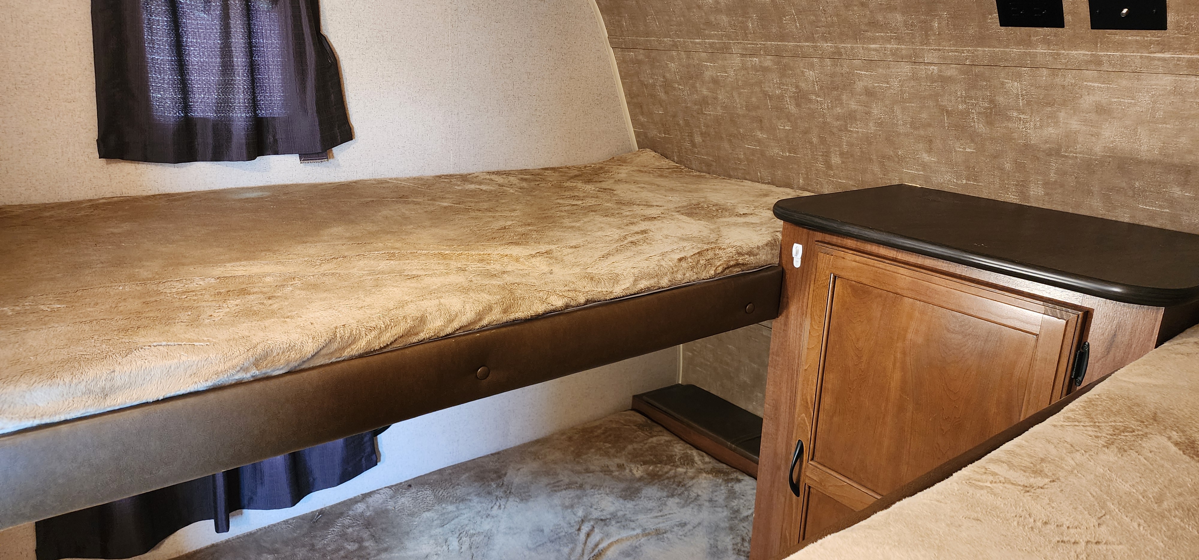 Interior of an RV rental showing cozy bunk beds with plush bedding and a nearby storage cabinet.. Jayco Jay Flight 2016