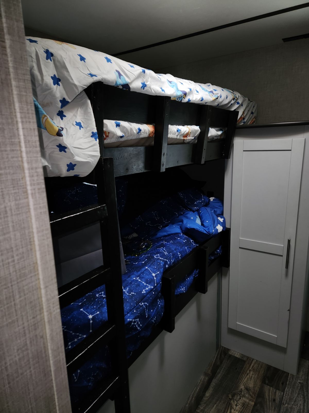 RV rental bunk beds: Cartoon sheets on top, constellation bedding below. A cozy, compact sleeping area with a wardrobe.. Keystone RV Bullet Ultra Lite 2020