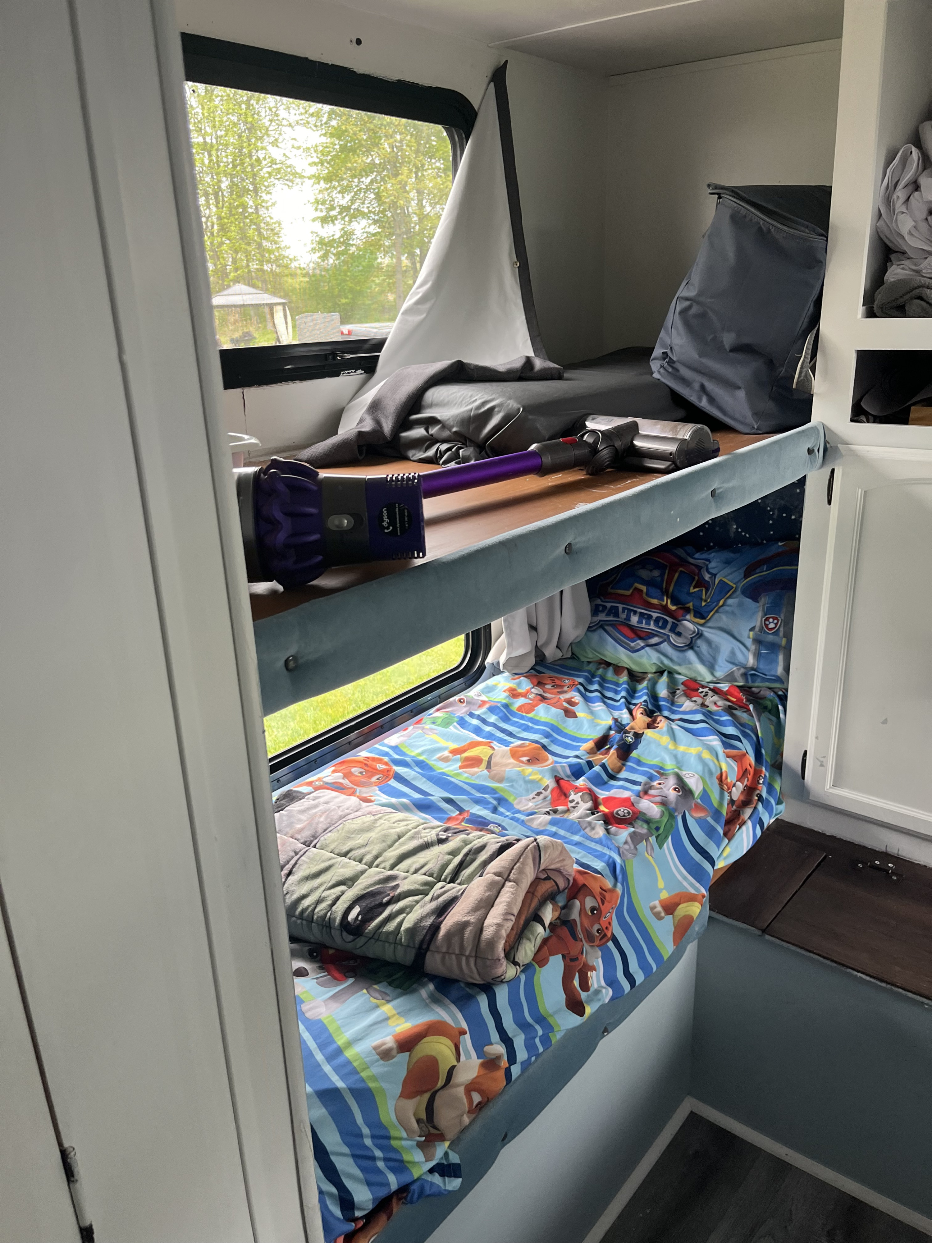 Cozy RV rental bunk beds, with Paw Patrol bedding on the lower bunk and a Dyson vacuum on the upper bunk.. Forest River Wildwood 2011