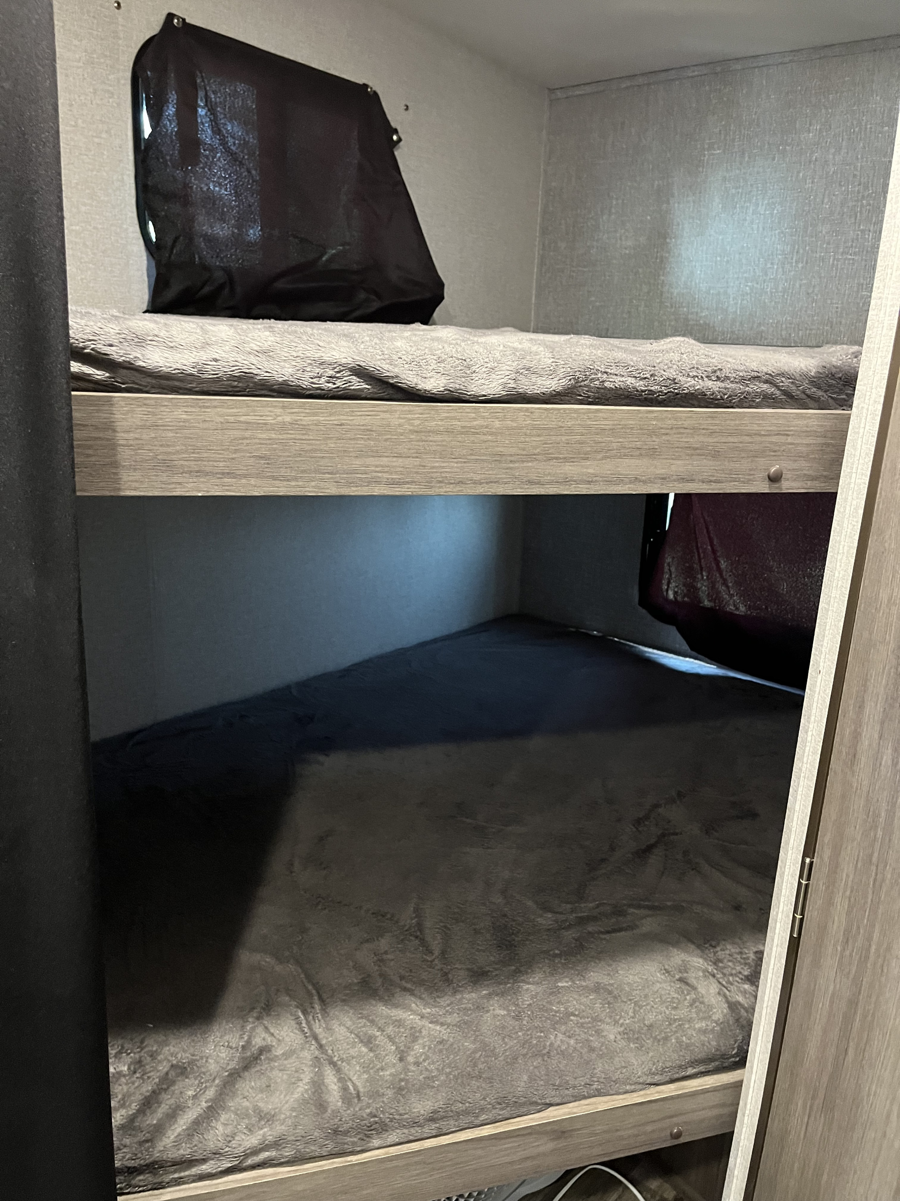 Inside an RV rental, showing comfortable bunk beds with grey blankets and blackout window covers.. Keystone RV 270BH 2022