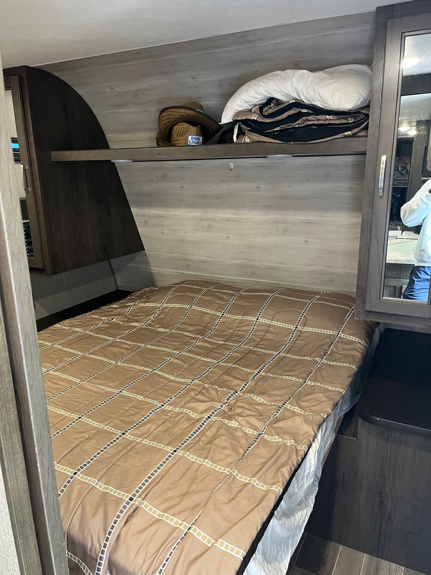 Inside an RV rental bedroom: cozy bed, shelf with hat & bedding, and overhead storage.. Jayco Jay Flight 2021